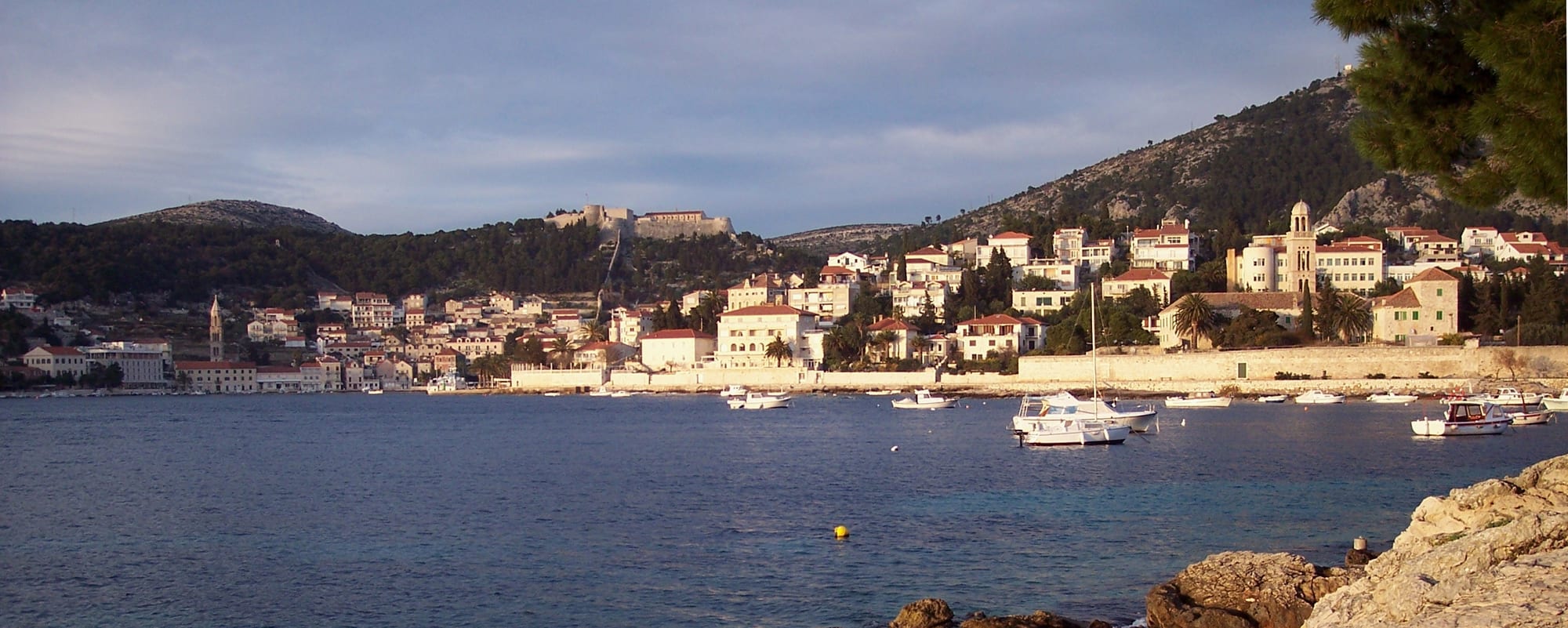 A harbour town of stone houses below a hilltop fortress, islands scattered in the bay beyond