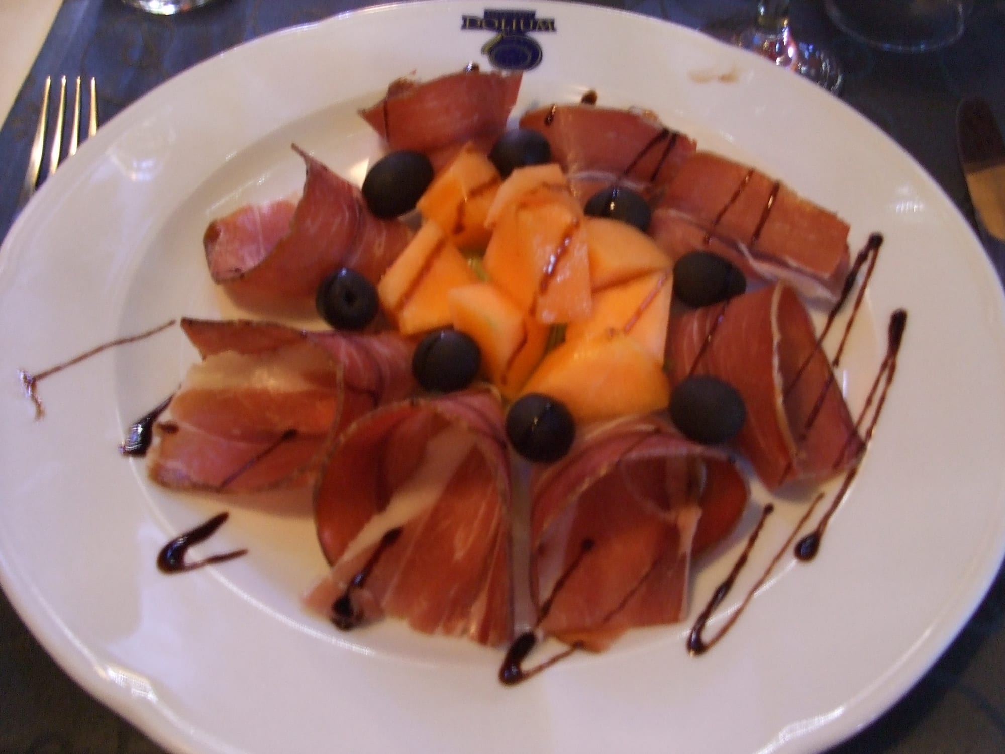 Thin slices of cured ham arranged on a plate with melon