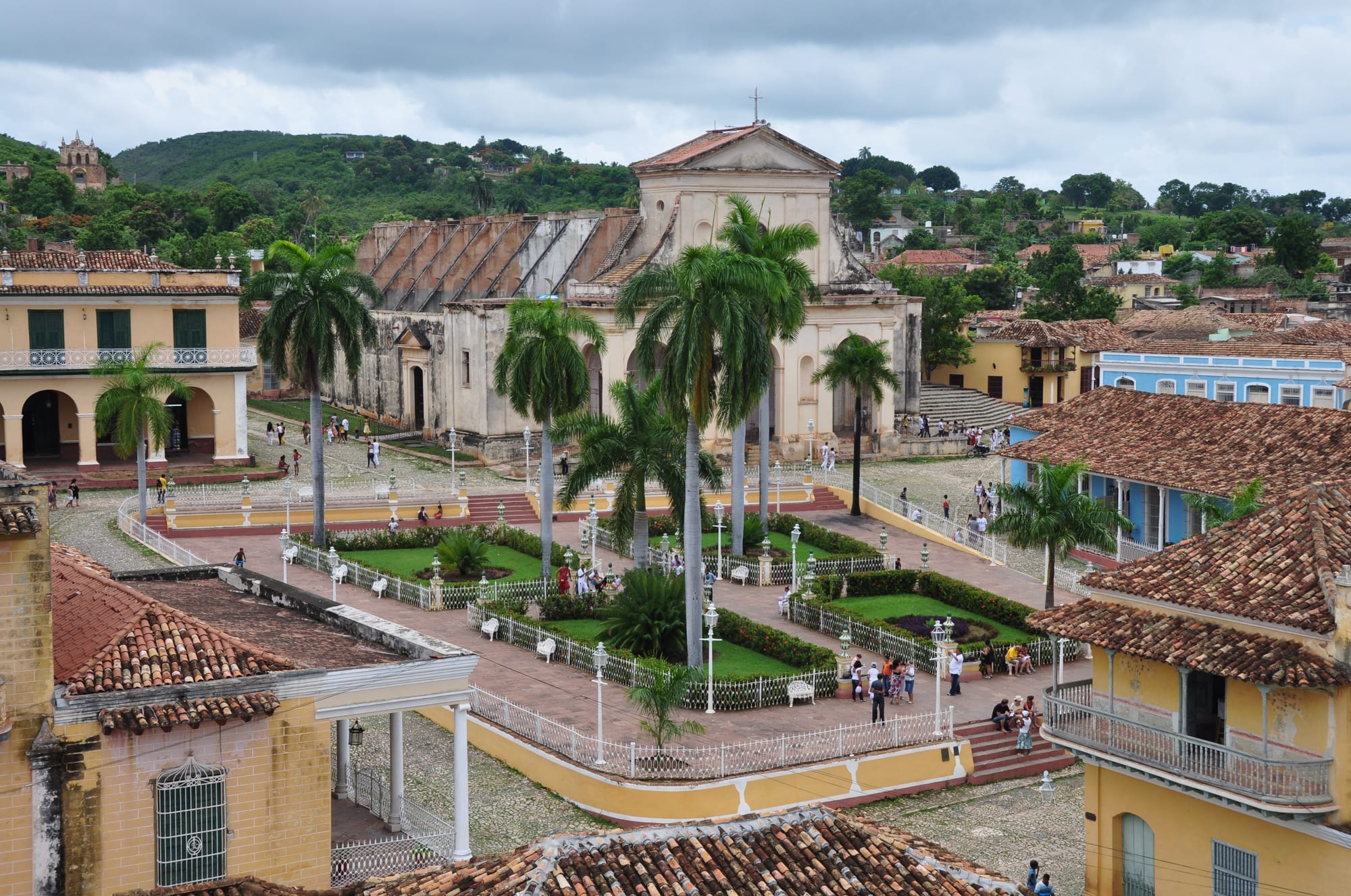 A colonial plaza with pastel houses, palm trees, and a church tower
