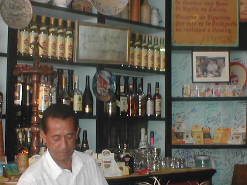 A bartender in a traditional bar pouring drinks from a tray of glasses