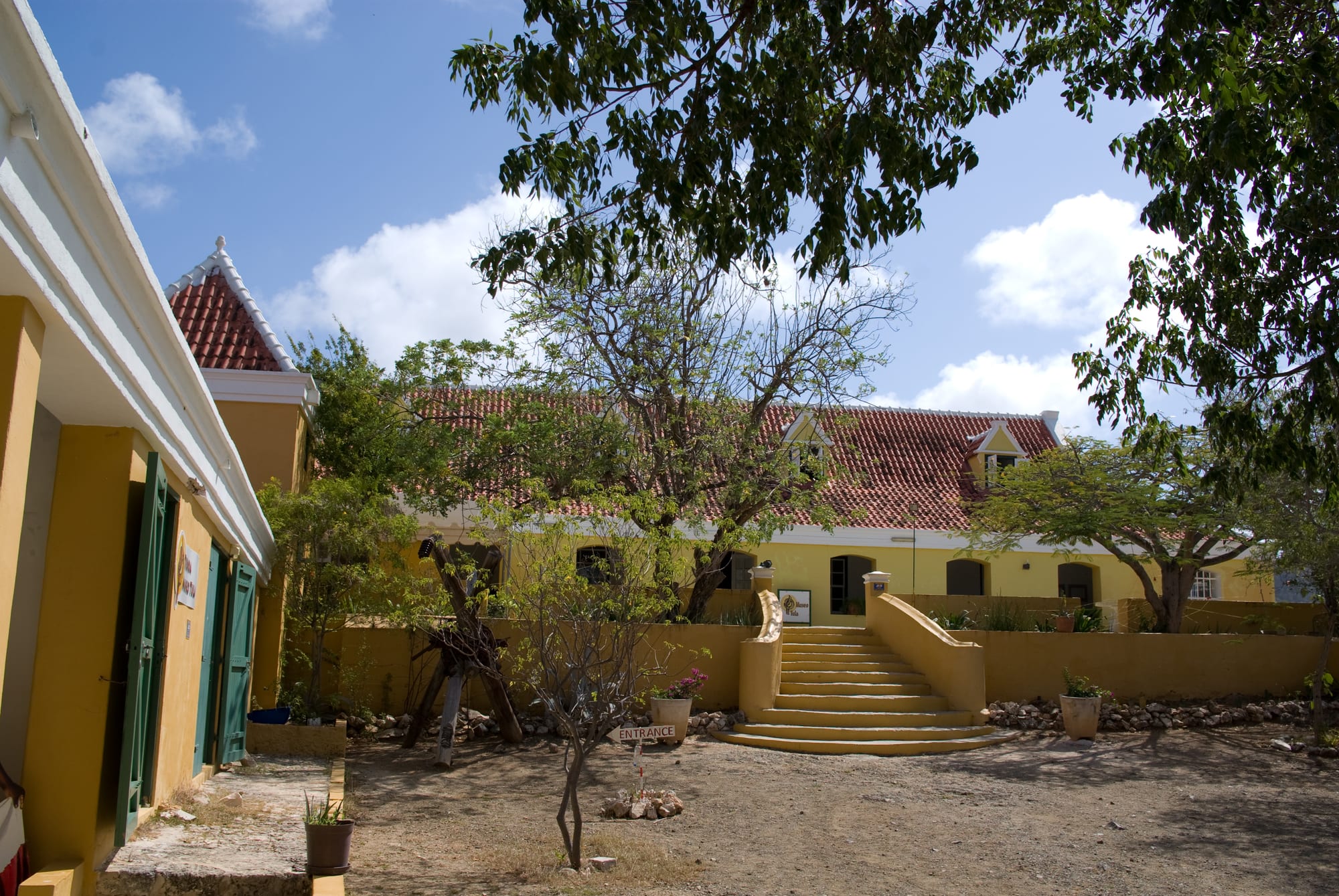 An ochre-and-white colonial plantation manor house against a dry, arid landscape