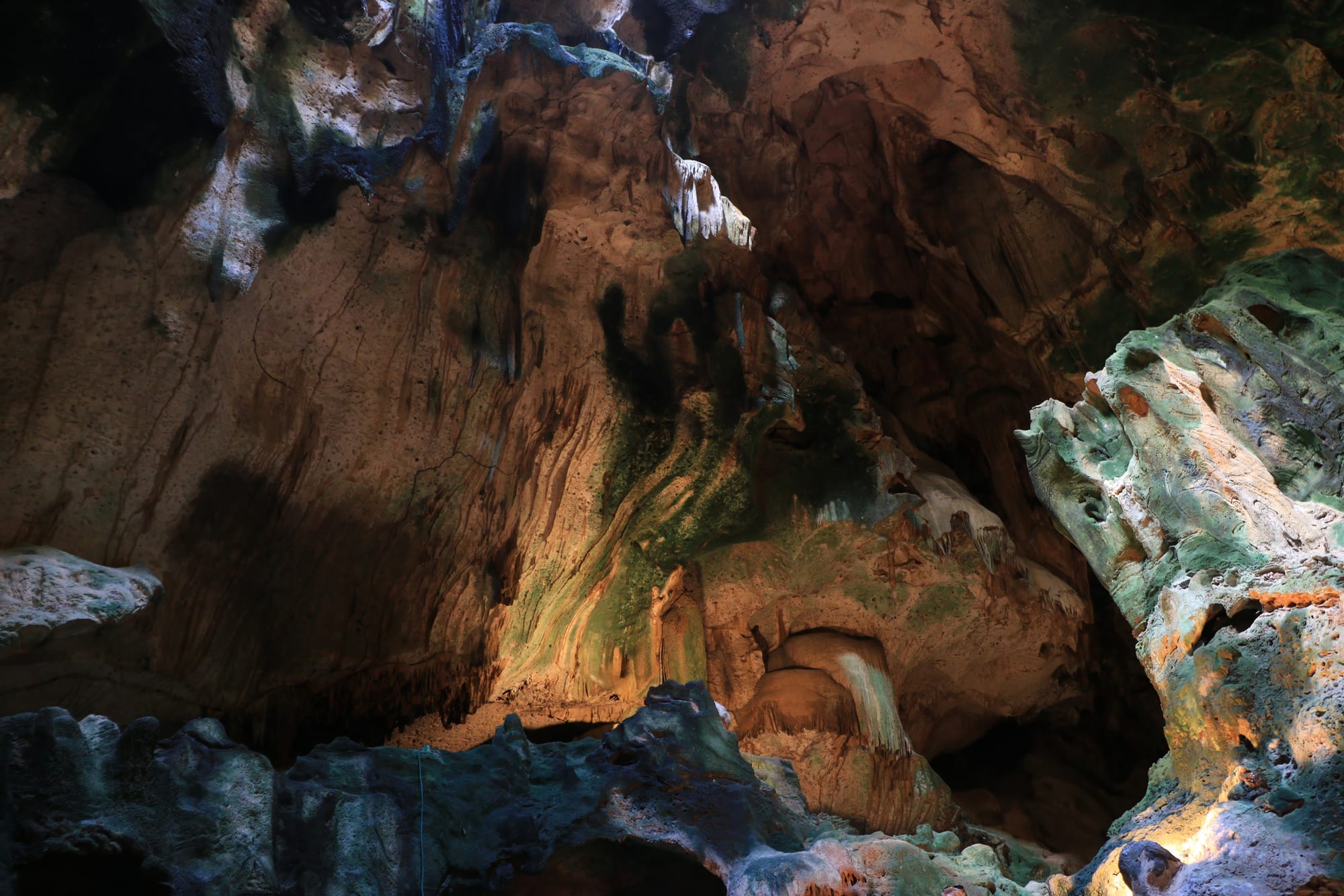 A limestone cavern with stalactites, flowstone and a small pool, lit for visitors