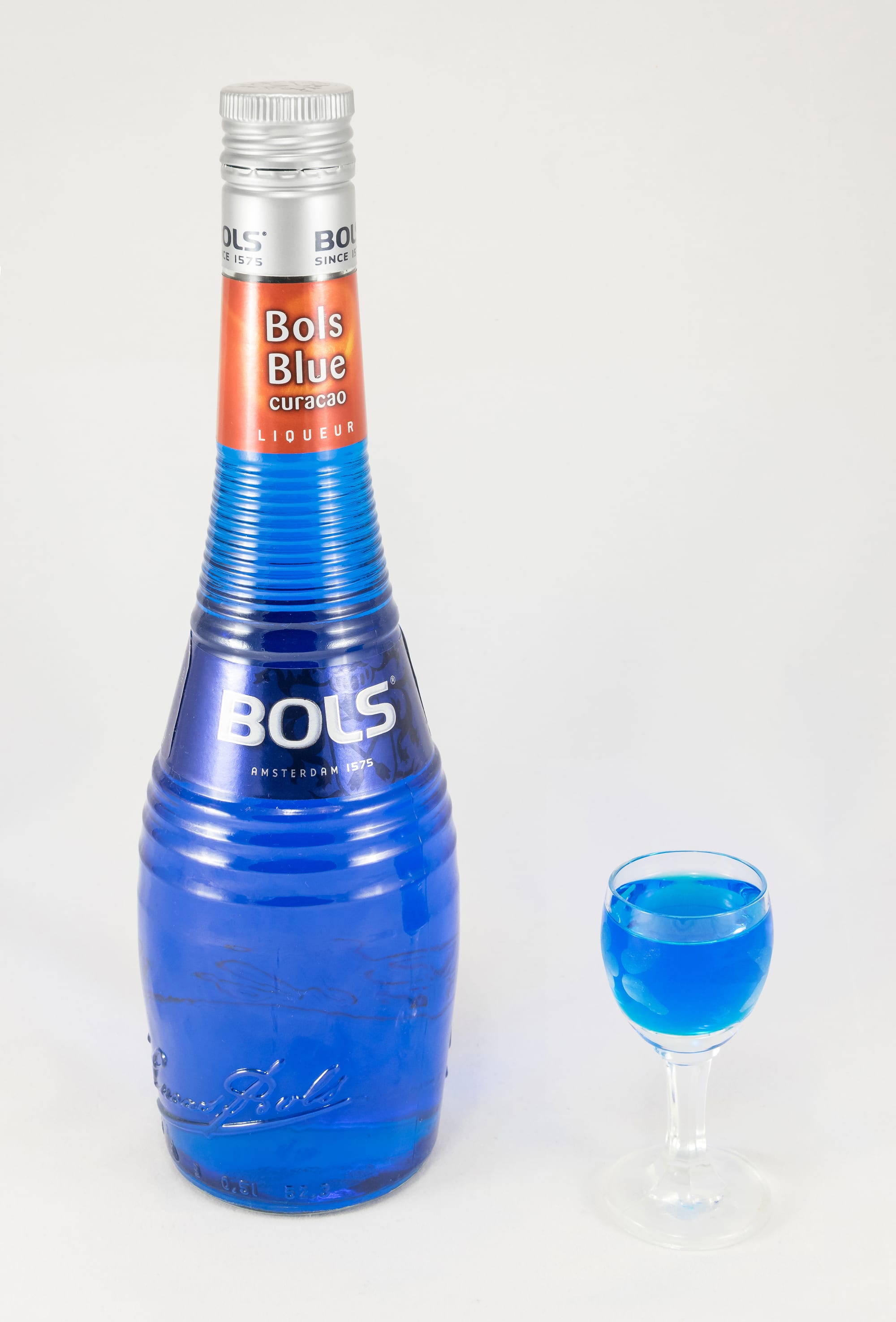 A tall bottle of bright blue liqueur