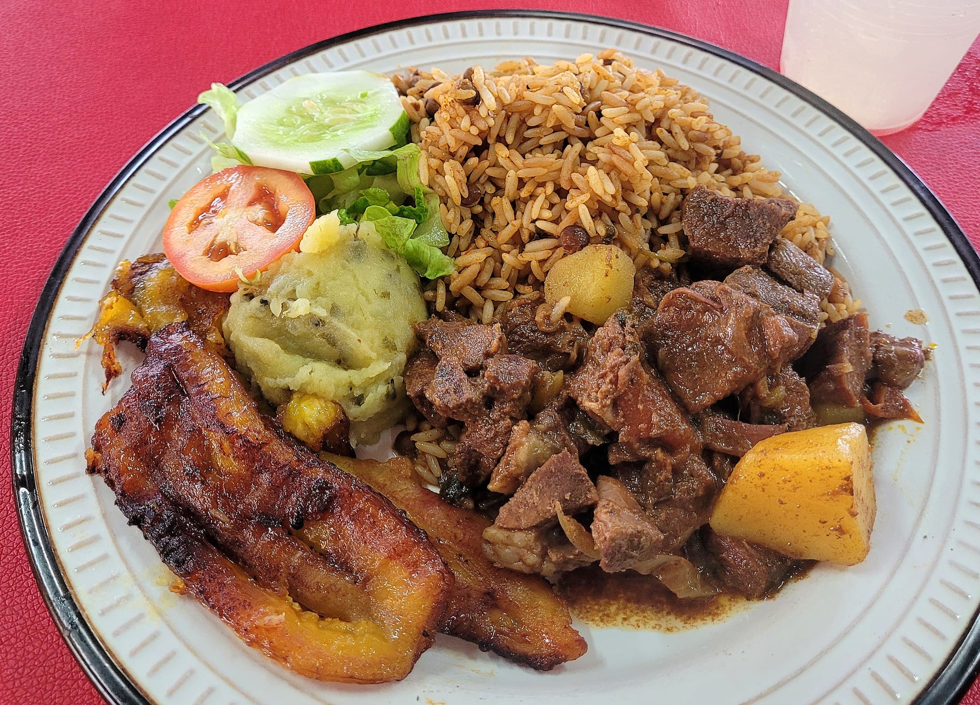 A plate of dark meat stew beside rice cooked with beans