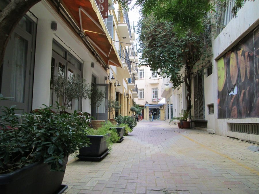 A quiet pedestrianised lane in old Nicosia lined with potted plants, small shops and cafe awnings