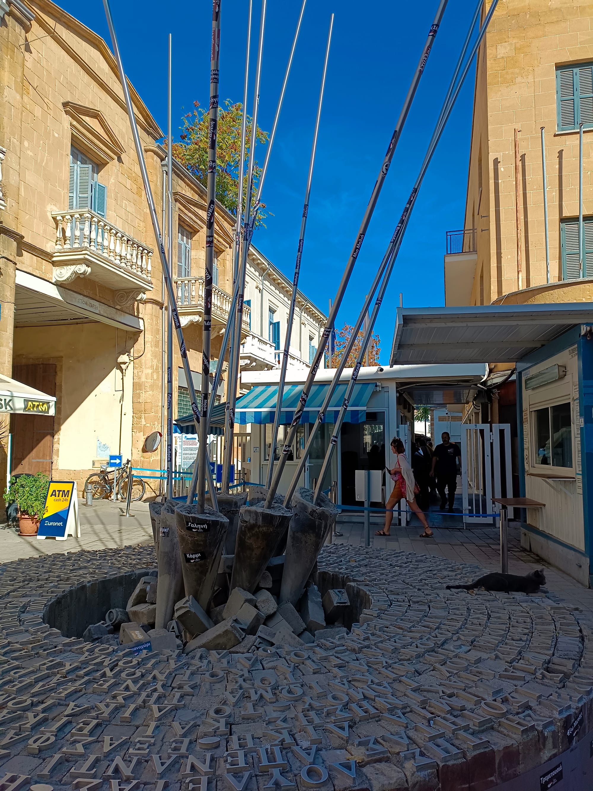 A pedestrian crossing point between two Cyprus jurisdictions on Ledra Street, with a small checkpoint booth, an ATM sign and people walking through