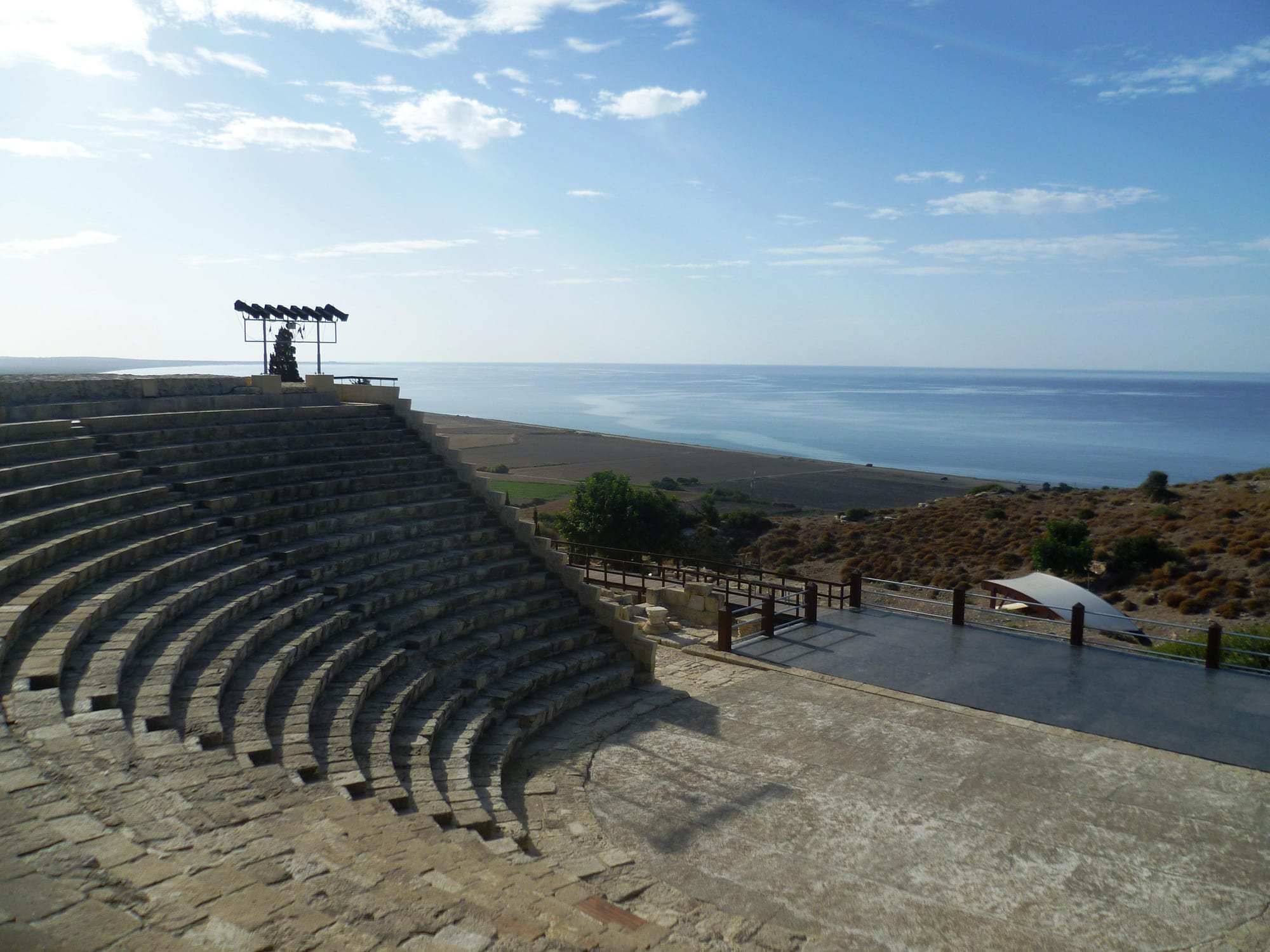 A restored Greco-Roman stone theatre on a clifftop with the sea far below