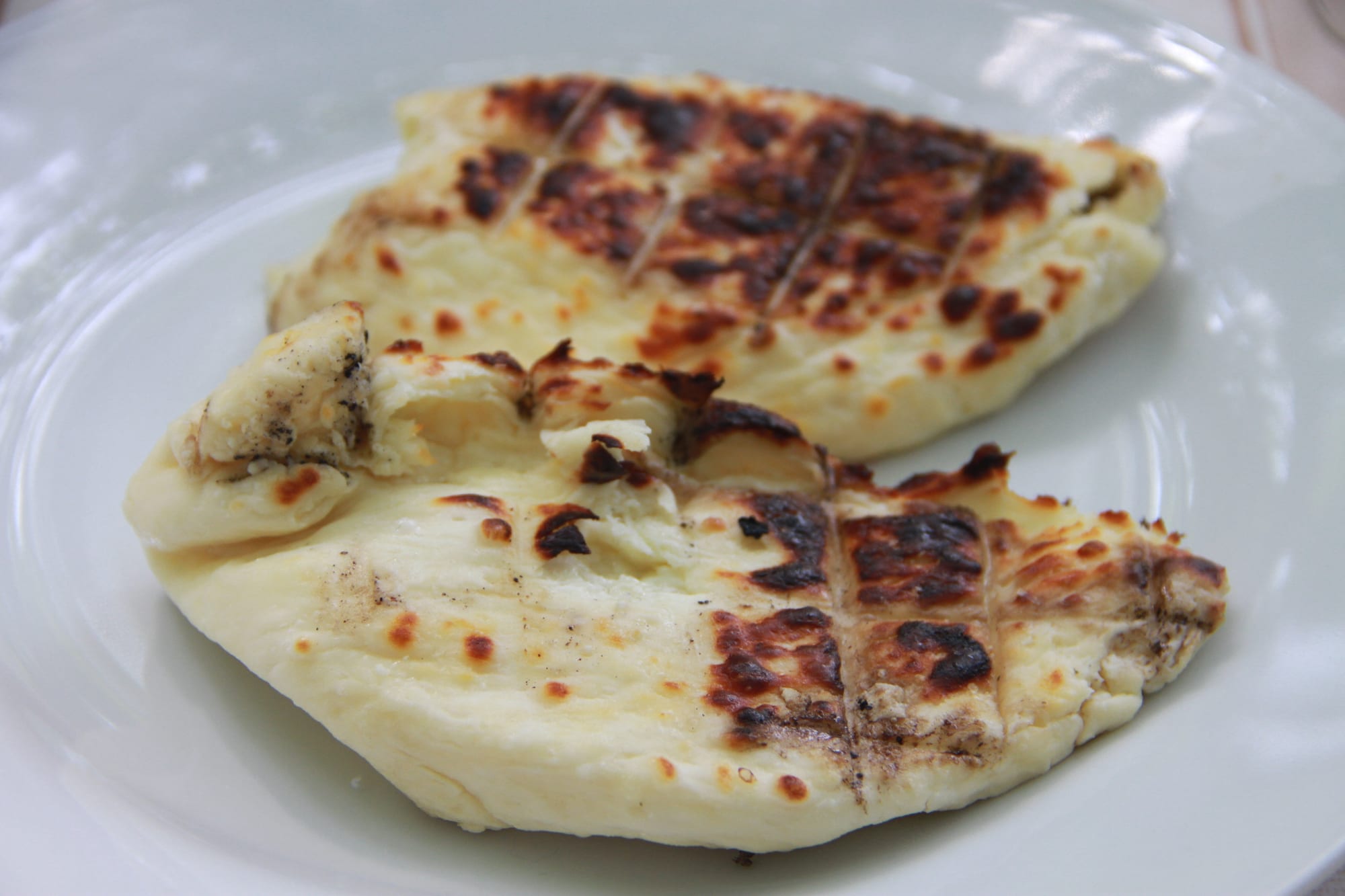 Slices of grilled cheese with dark char marks, on a plate