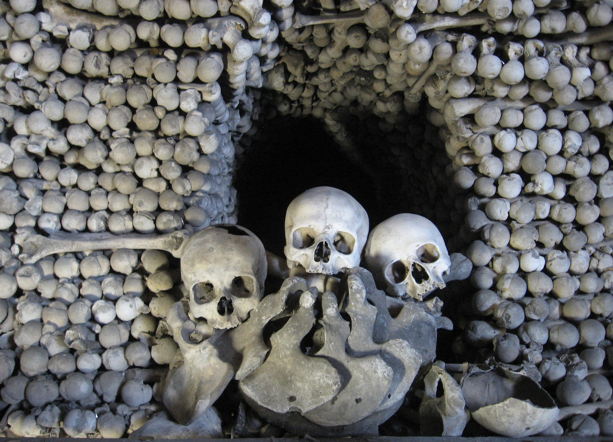 A chandelier and pyramids made entirely of human skulls and bones inside a chapel