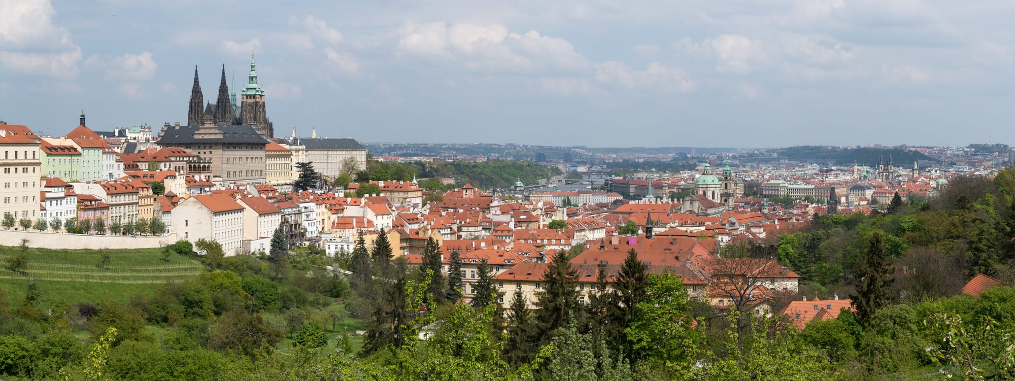 A tightly packed old city of red roofs, church towers and spires seen from a hill