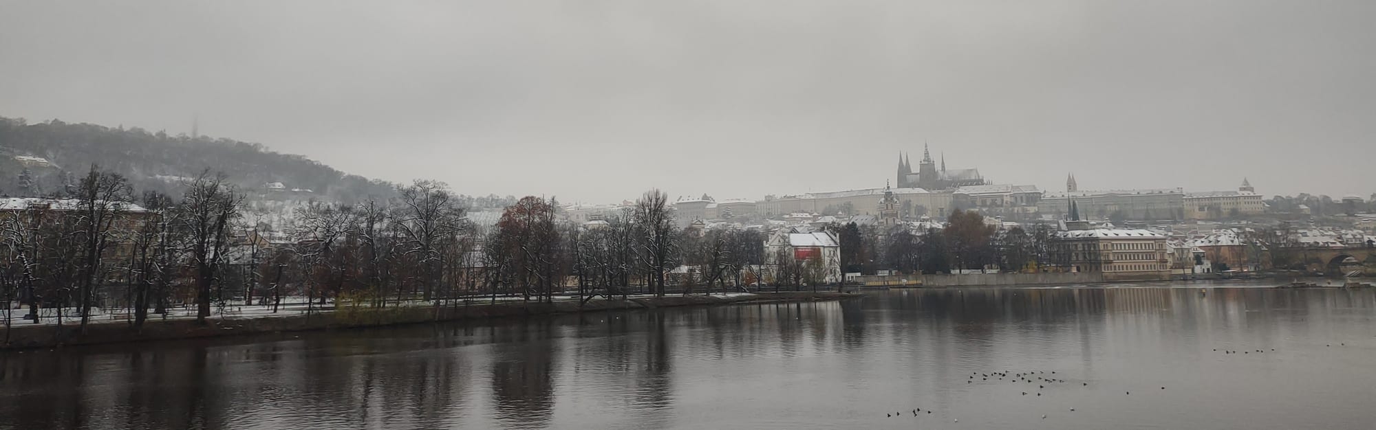 A hilltop complex of palaces and a Gothic cathedral spire above a river and red-roofed city
