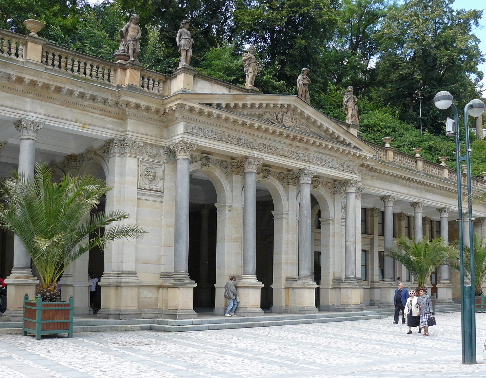 An ornate cast-iron colonnade over a hot spring, in a valley town of pastel buildings