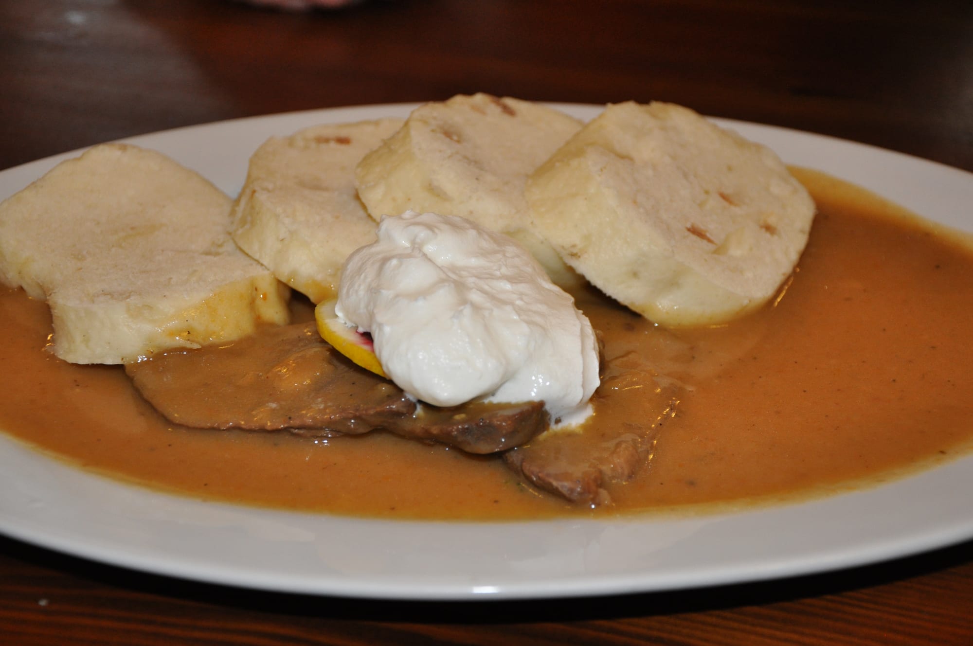 Slices of beef in a pale creamy sauce, served with dumplings
