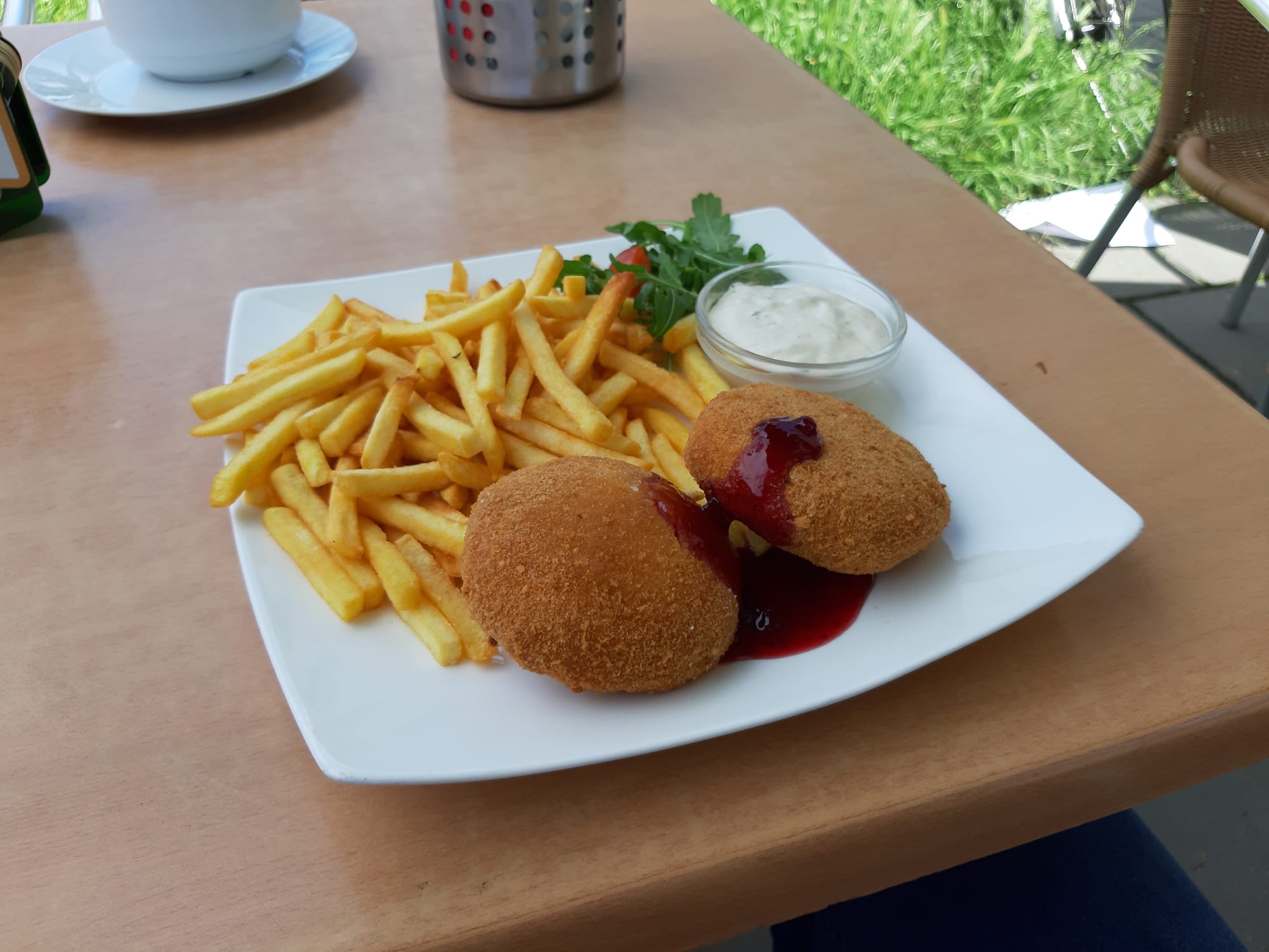 A breaded, deep-fried slab of cheese on a plate with fries and tartar sauce