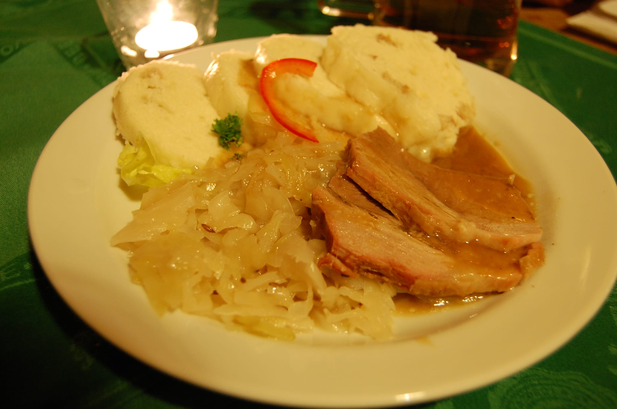 A plate of roast pork slices with bread dumplings and cooked cabbage