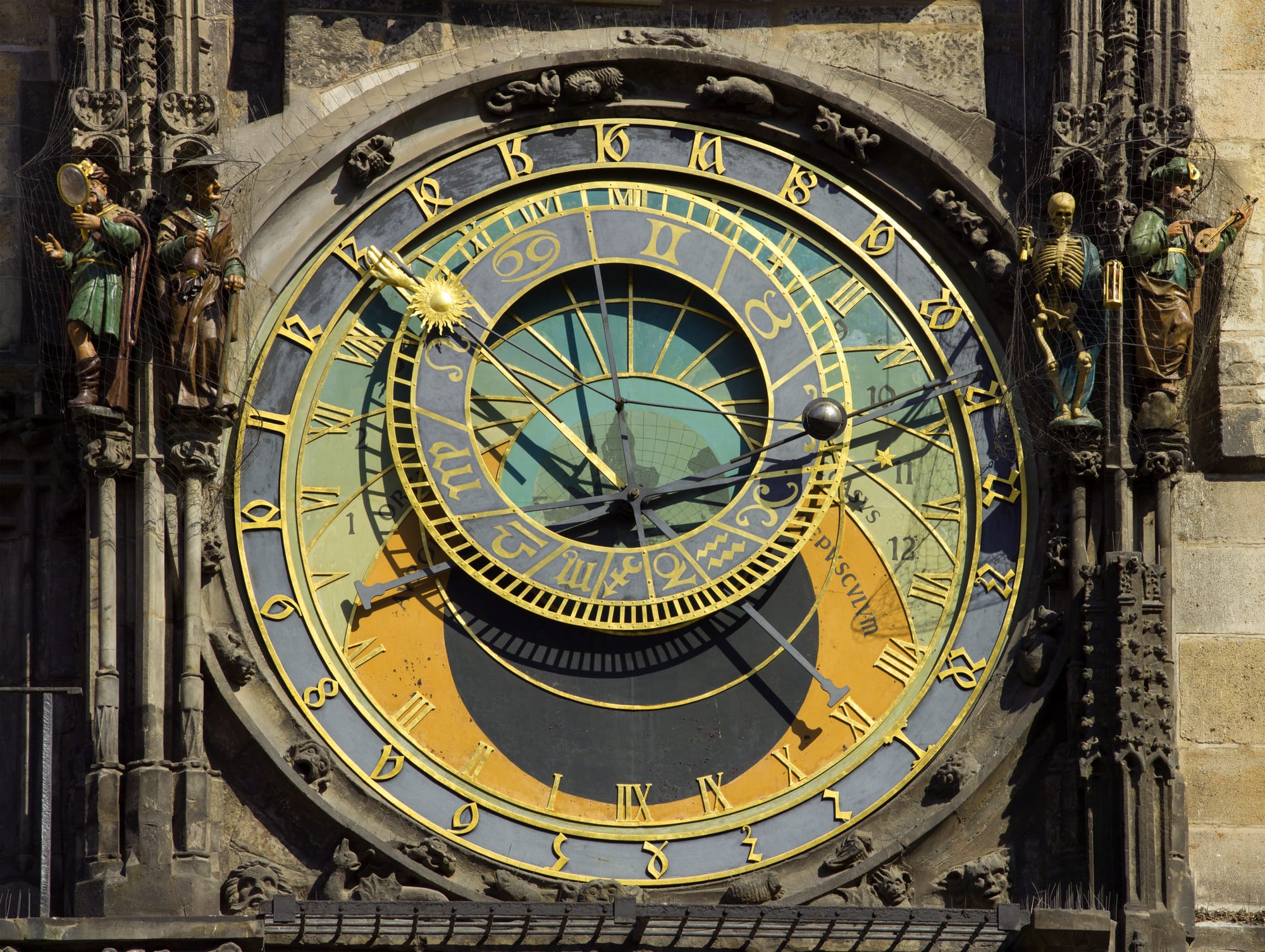 An elaborate medieval astronomical clock face with gilded zodiac dials on a Gothic tower wall