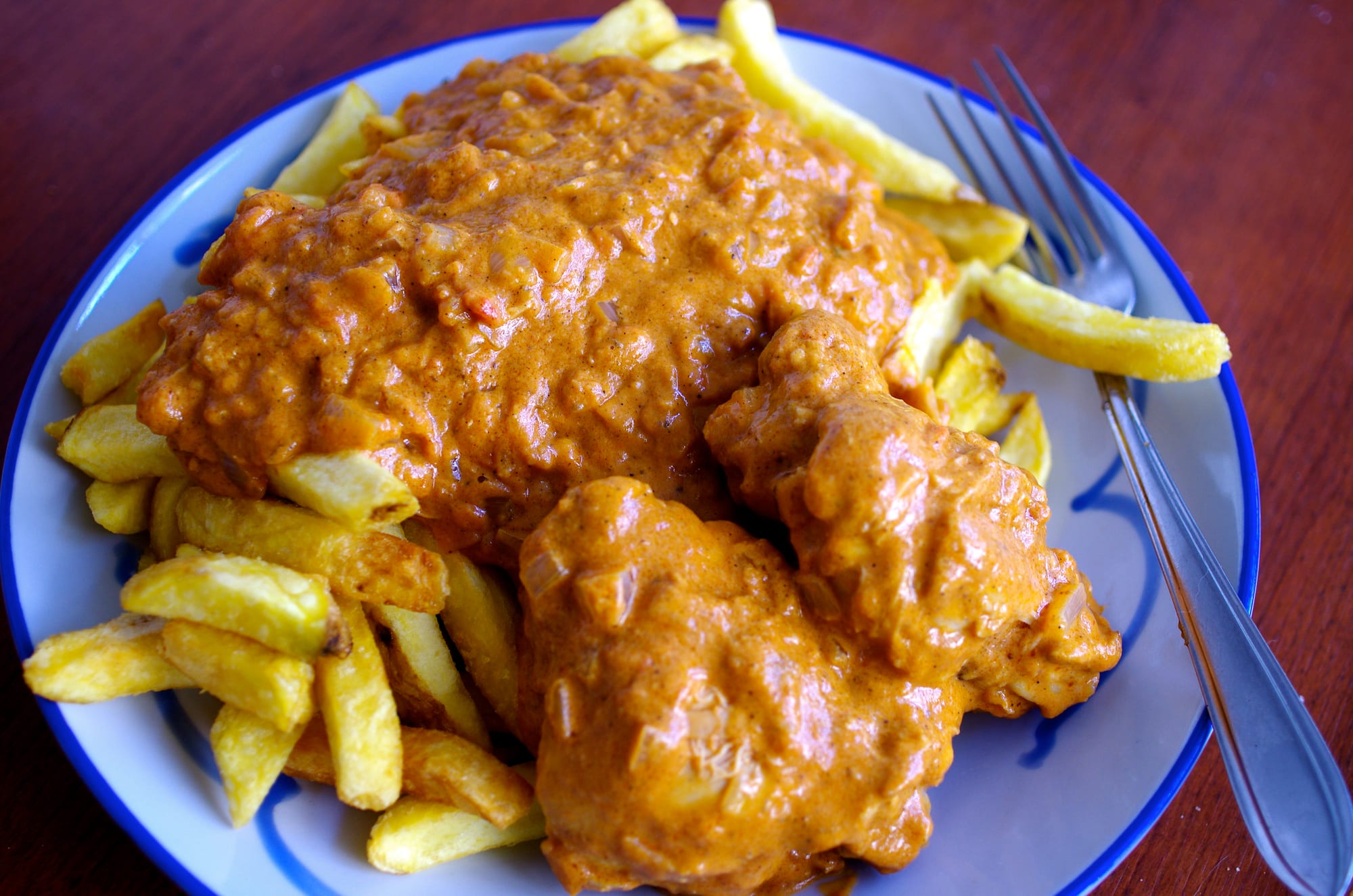 Pieces of chicken in an orange sauce served with fries