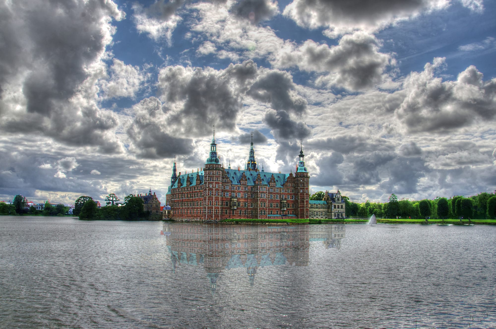 A grand red-brick and sandstone palace on islands in a lake, with towers and spires
