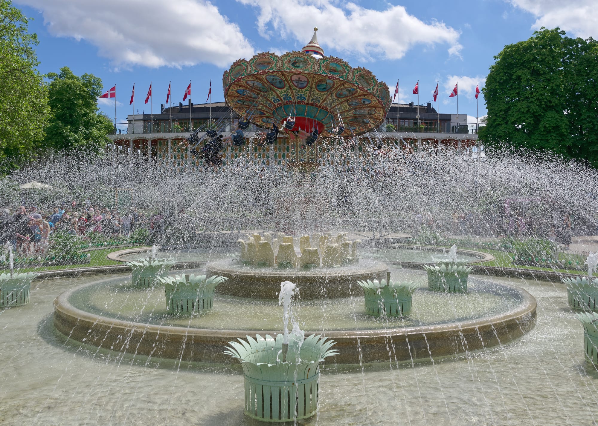 An ornamental fountain and pavilions in a landscaped amusement park with mature trees