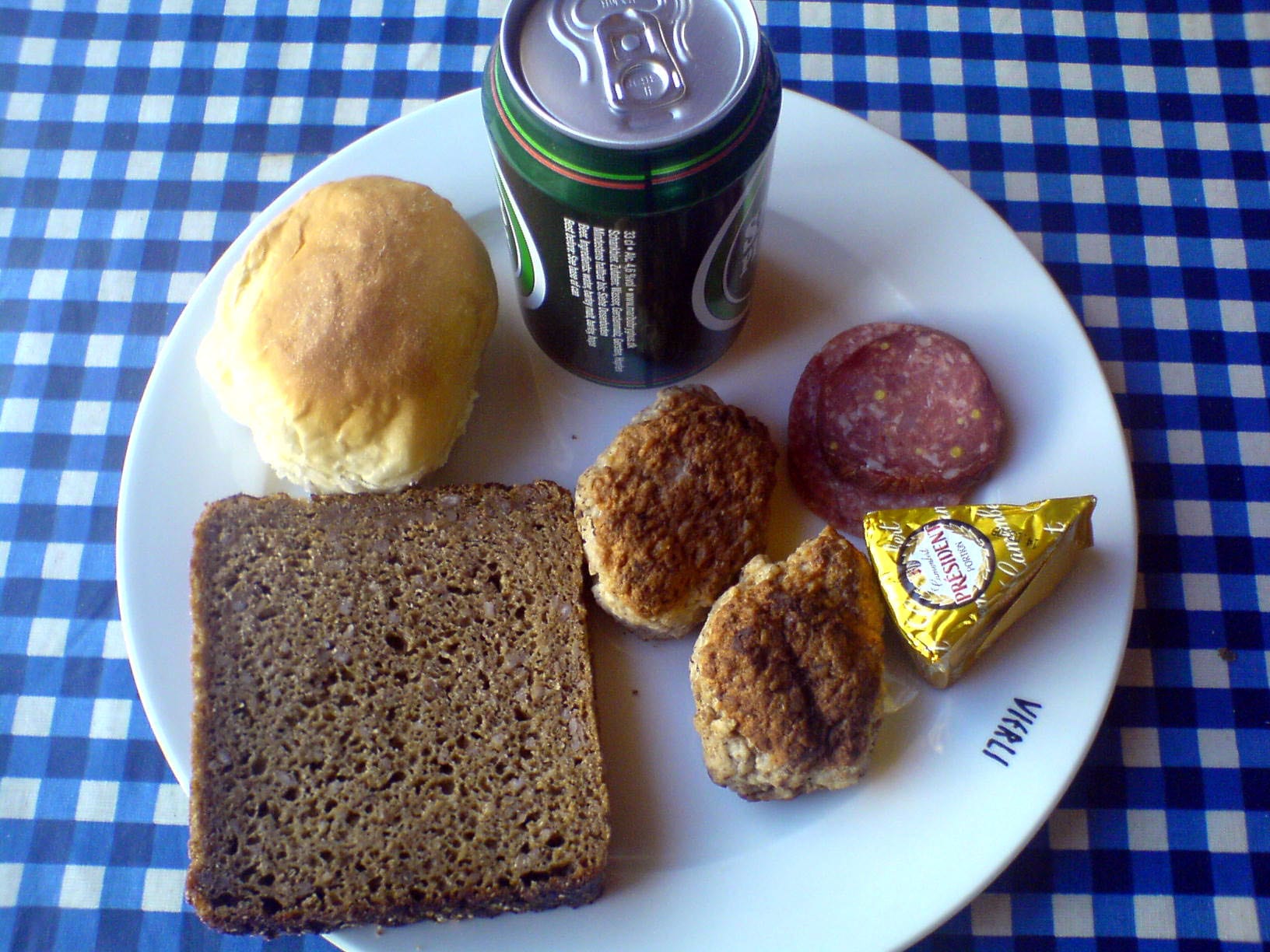 A spread of rye bread, a roll, meatballs, sausage, cheese and a glass of beer