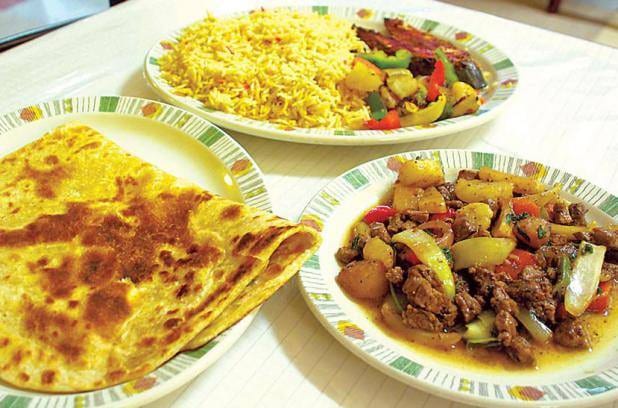 A plate of rice, fish, liver and vegetables served with flatbread