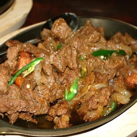 A dish of small pan-fried meat pieces with onion and pepper