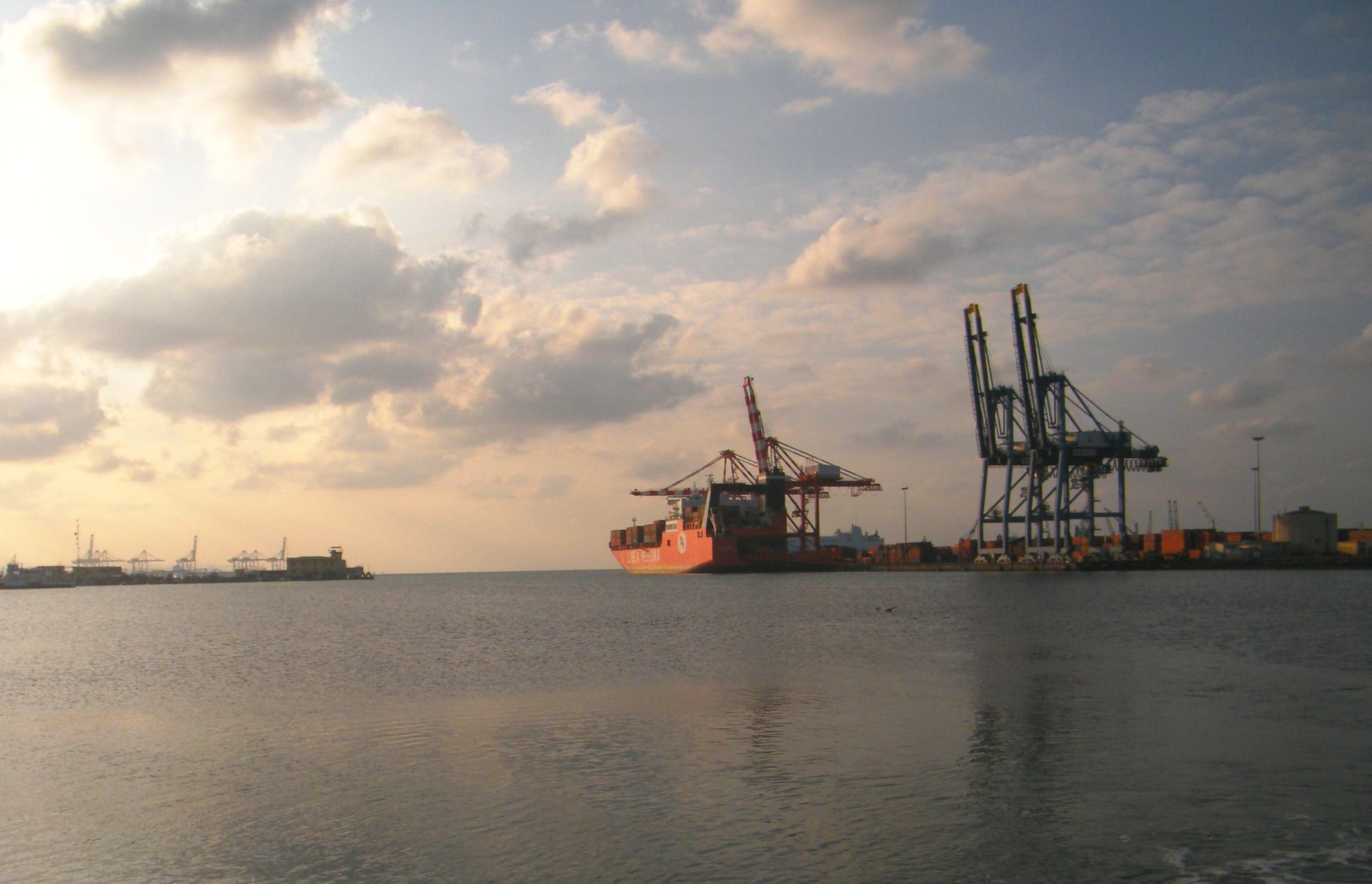 Rows of stacked shipping containers and gantry cranes along a modern port quay