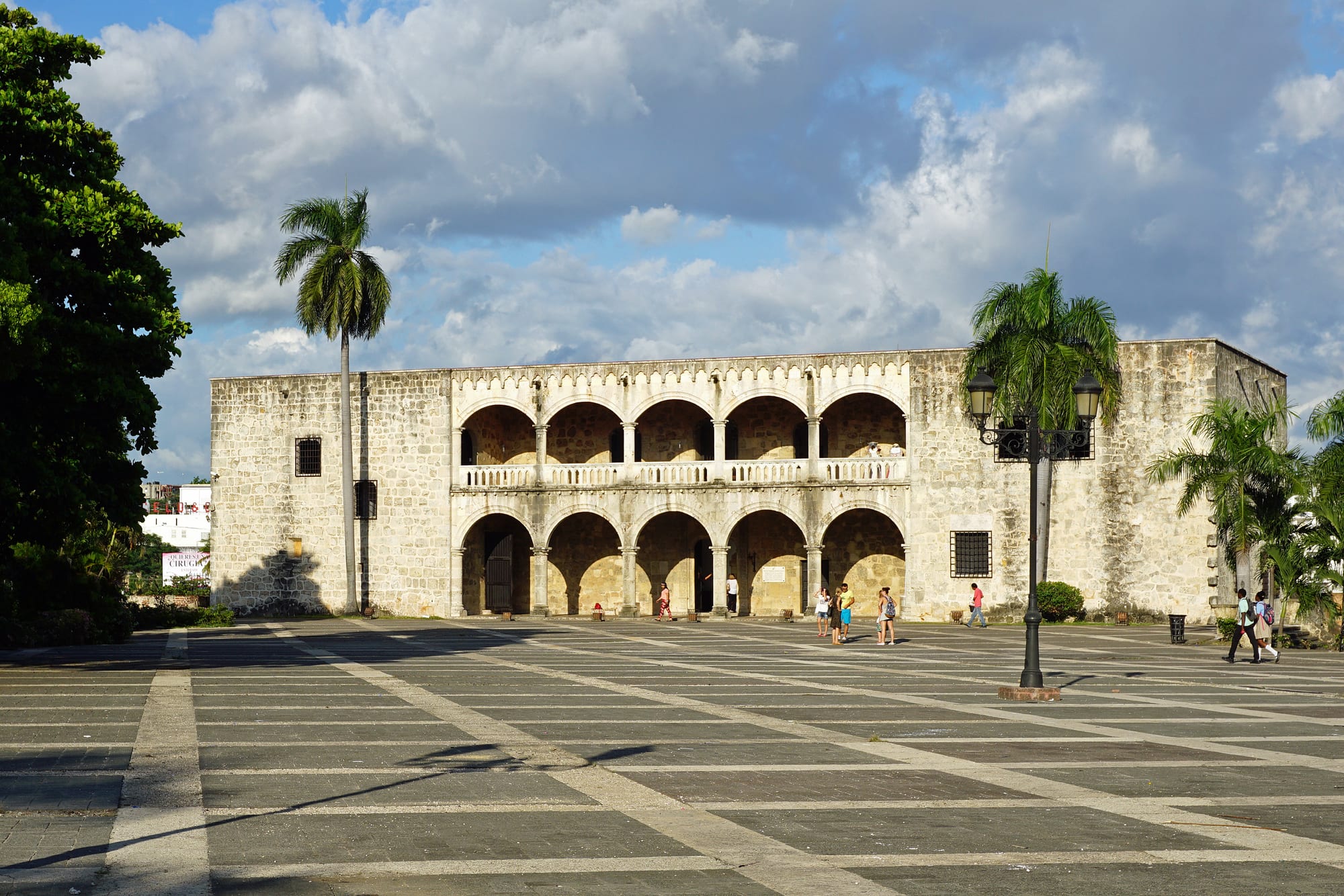 A blocky Renaissance stone palace with loggias, at the head of a colonial plaza