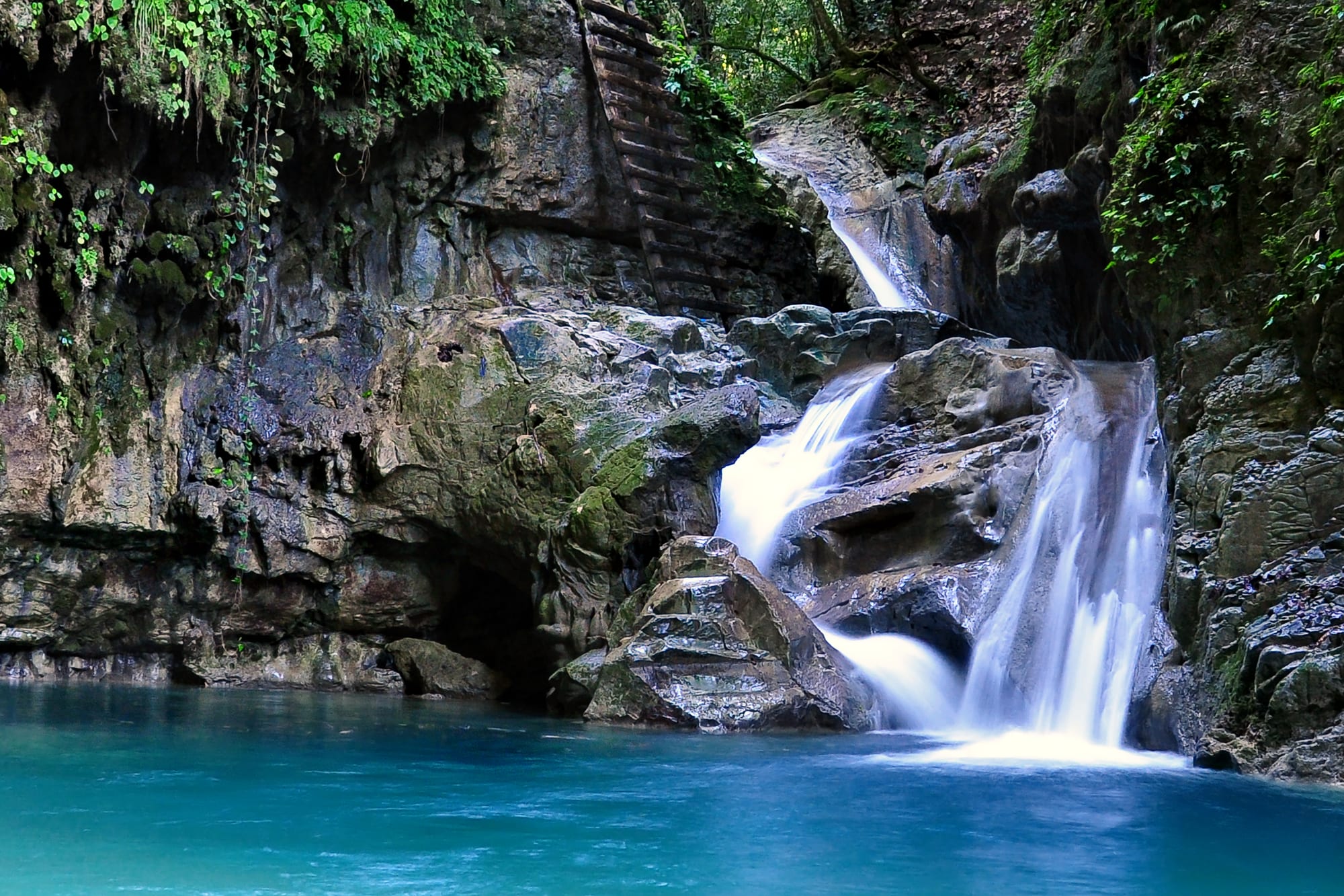 A waterfall cascading into a turquoise pool within a rock canyon