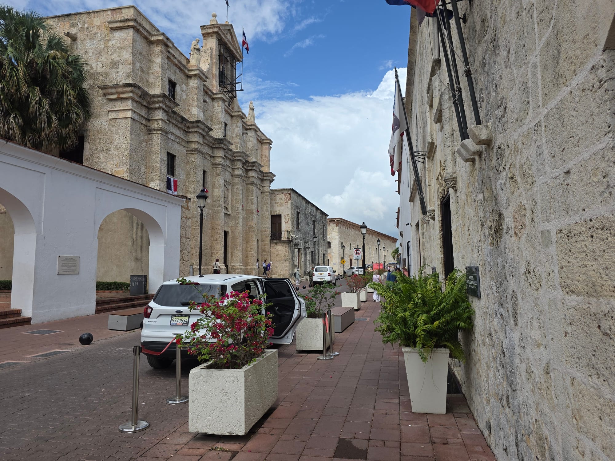A narrow cobbled street of low colonial buildings with iron lamps and shuttered windows