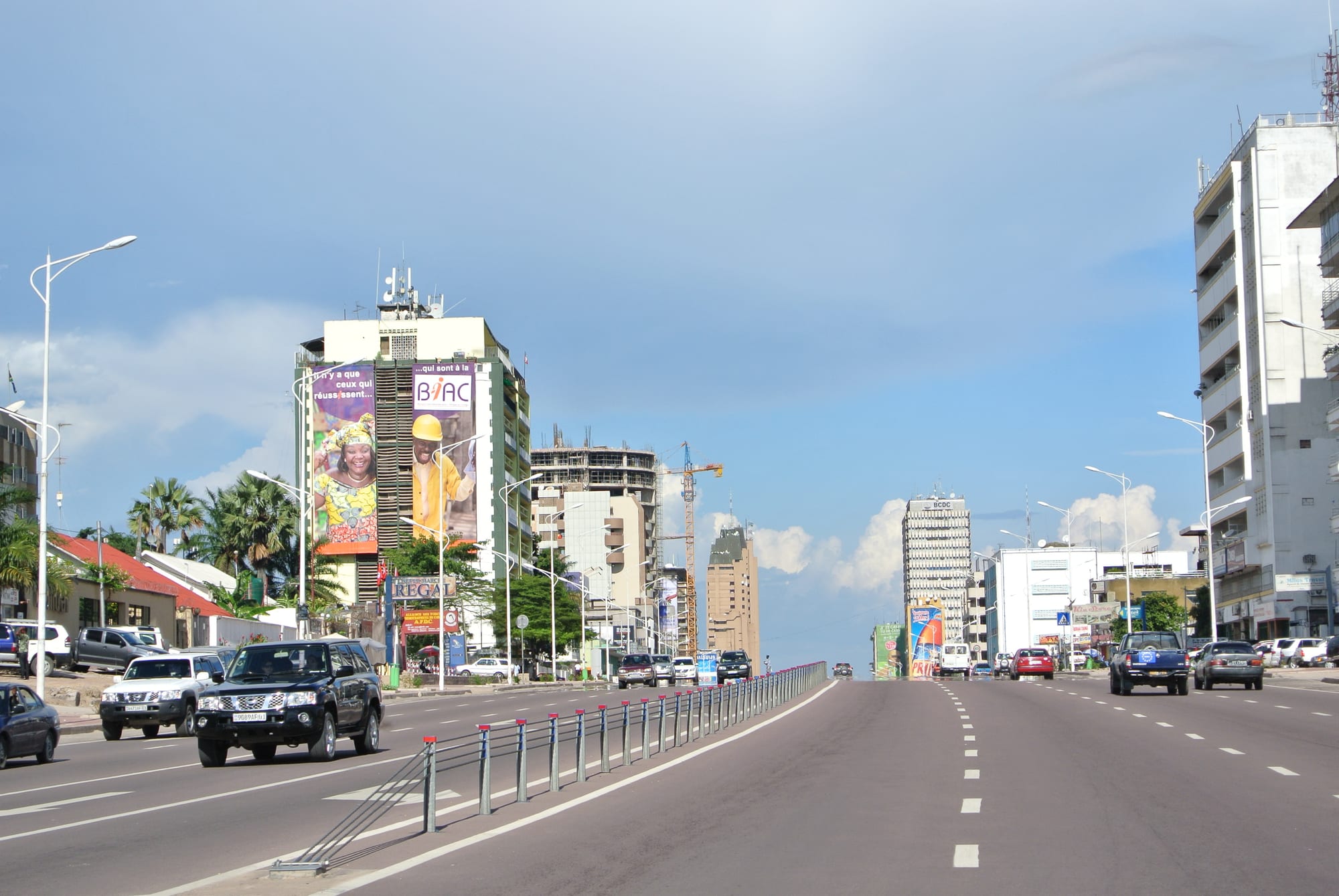 A wide multi-lane boulevard with high-rise buildings and heavy traffic in a large African city