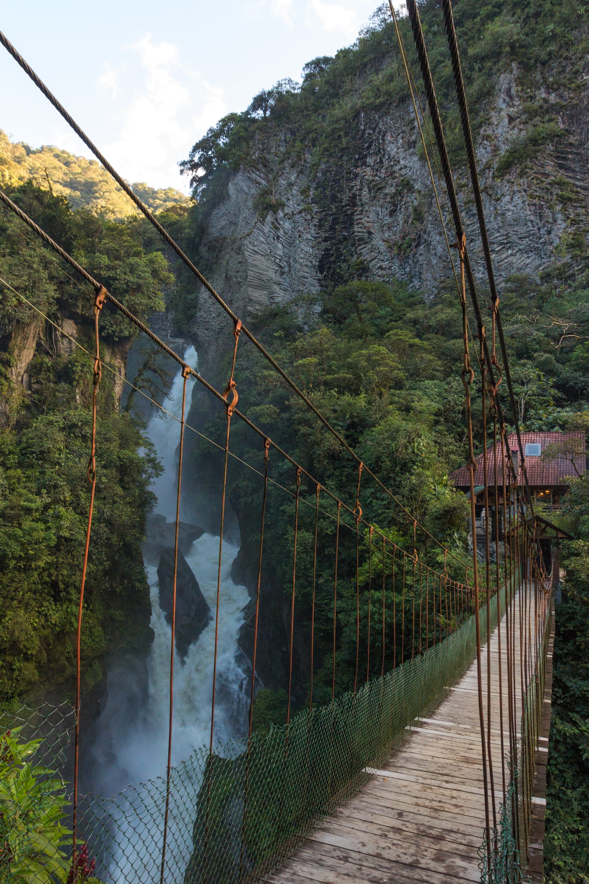 A powerful waterfall crashing through a narrow rock gorge with a footbridge across the top