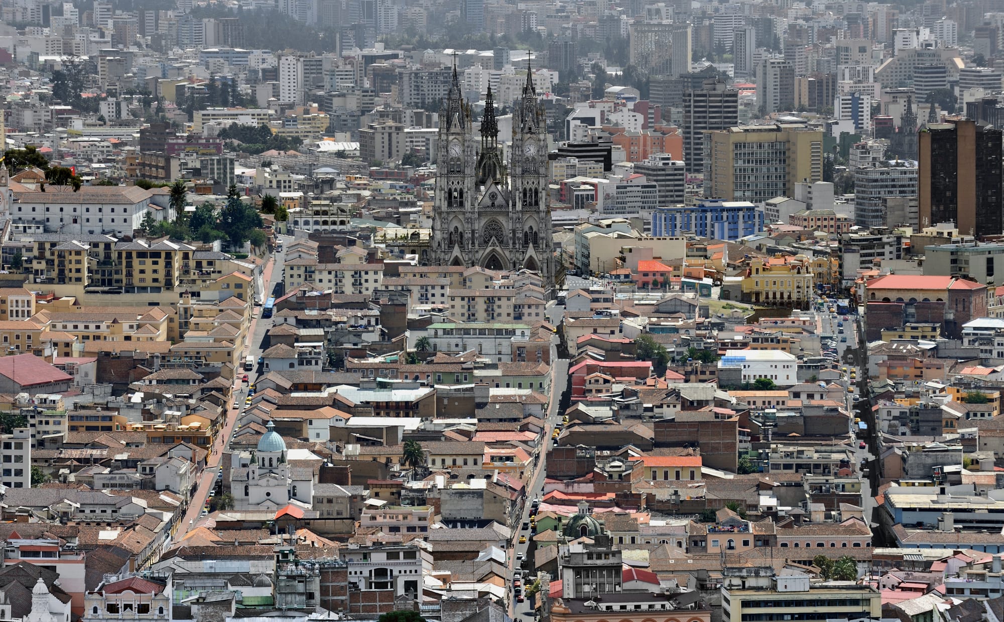 A dense colonial city of white buildings and church domes filling a high valley, mountains around
