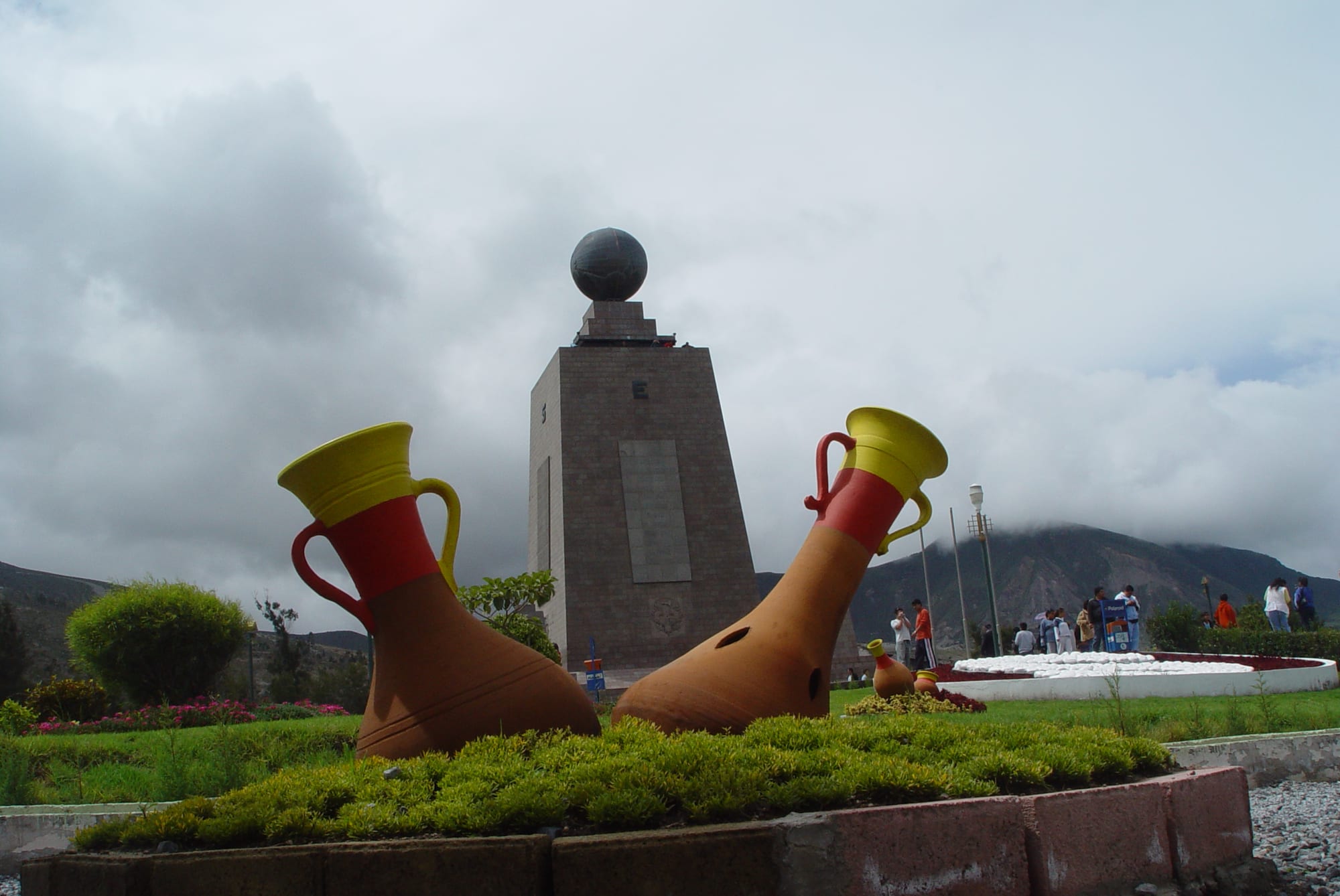 A large stone monument topped by a globe, with a yellow line running away from it across a plaza