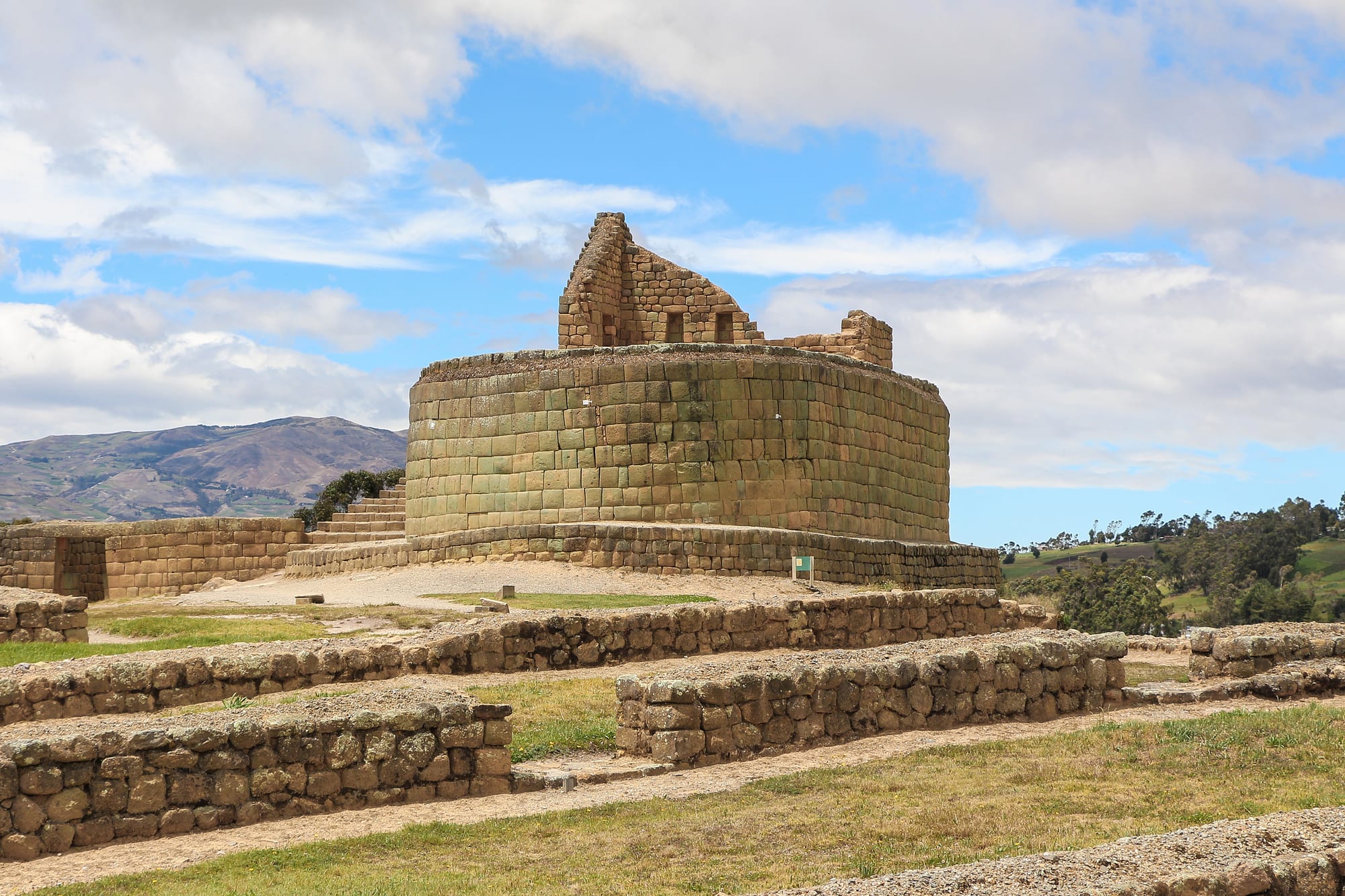 An oval platform of finely fitted Inca stonework on a grassy Andean hillside