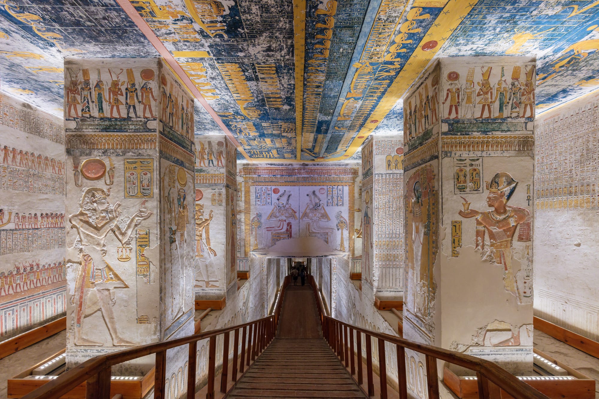 A painted tomb corridor with a vaulted, star-covered ceiling and hieroglyph-covered walls