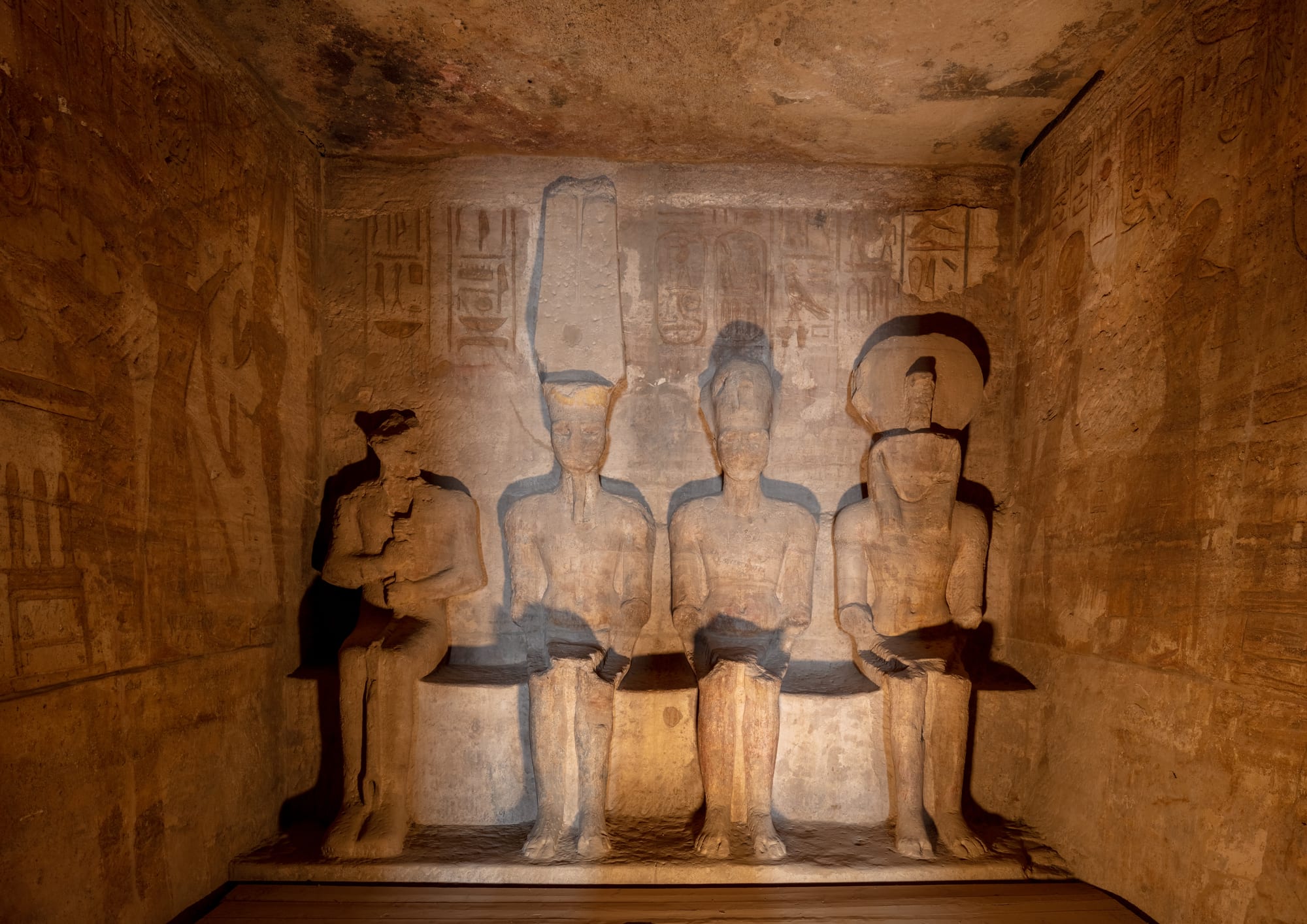 Four enormous seated pharaoh statues carved into a rock face, flanking a temple entrance