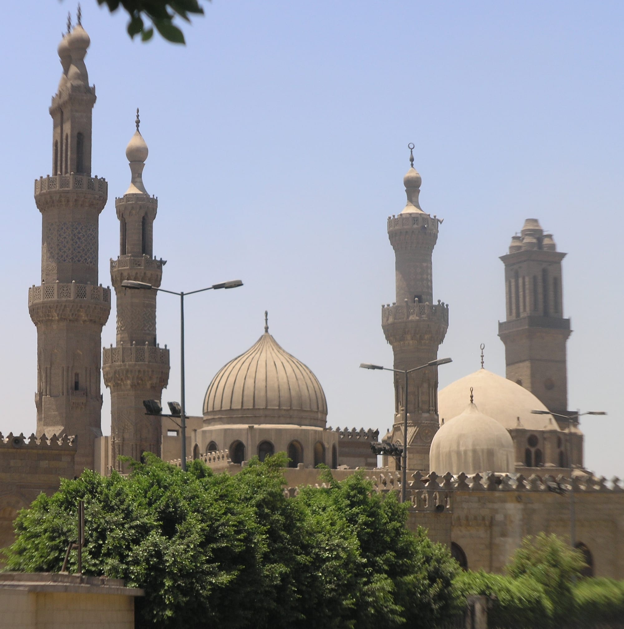 A sand-coloured mosque with several minarets and a large arcaded courtyard