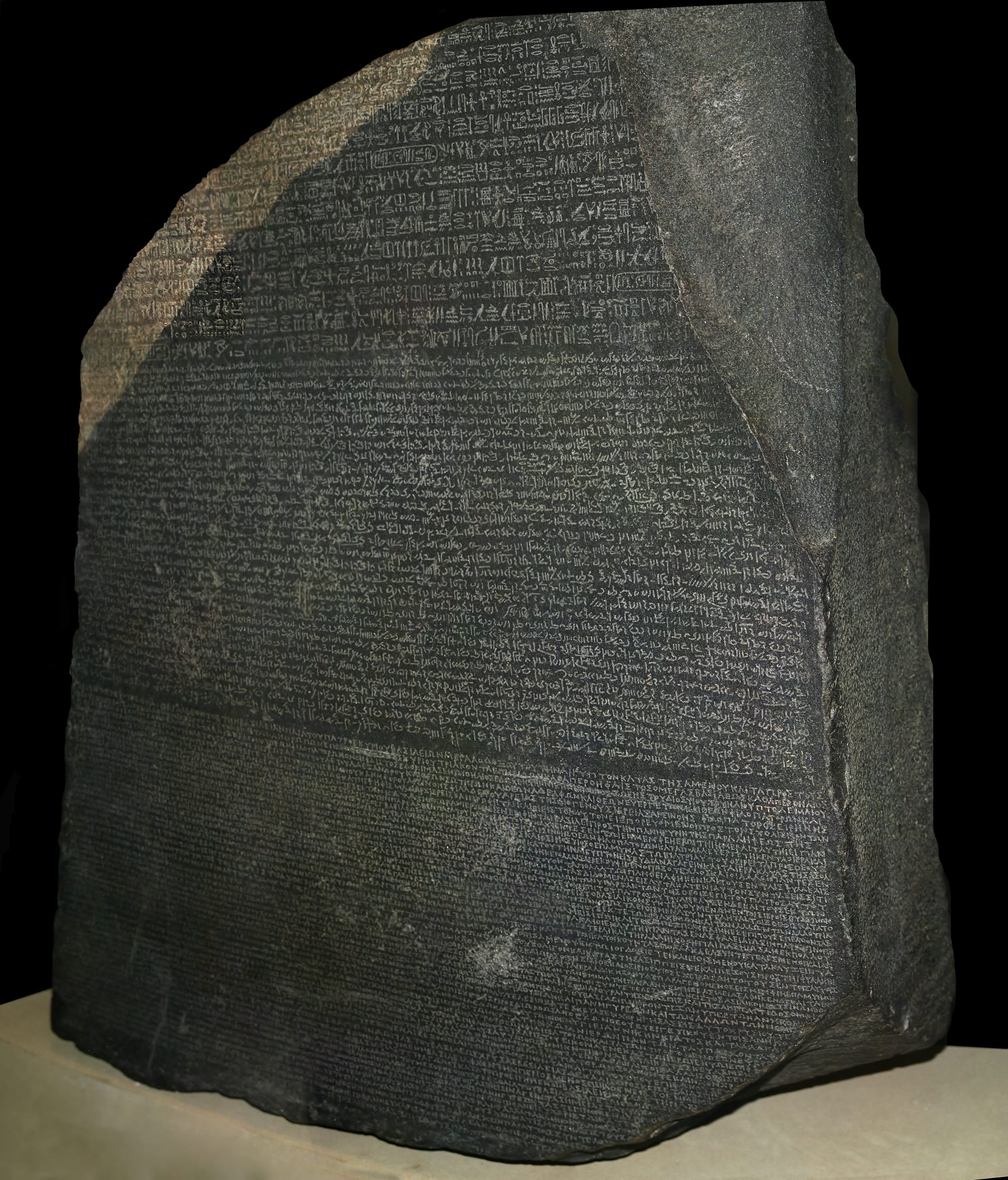 A large dark granite slab densely carved with three bands of different scripts