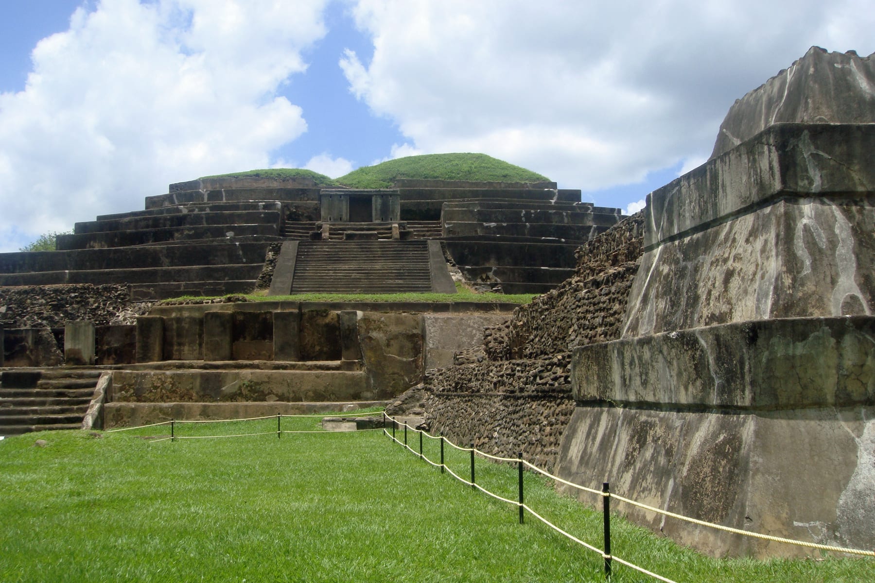 A restored stepped stone-and-concrete pyramid among lawns and trees