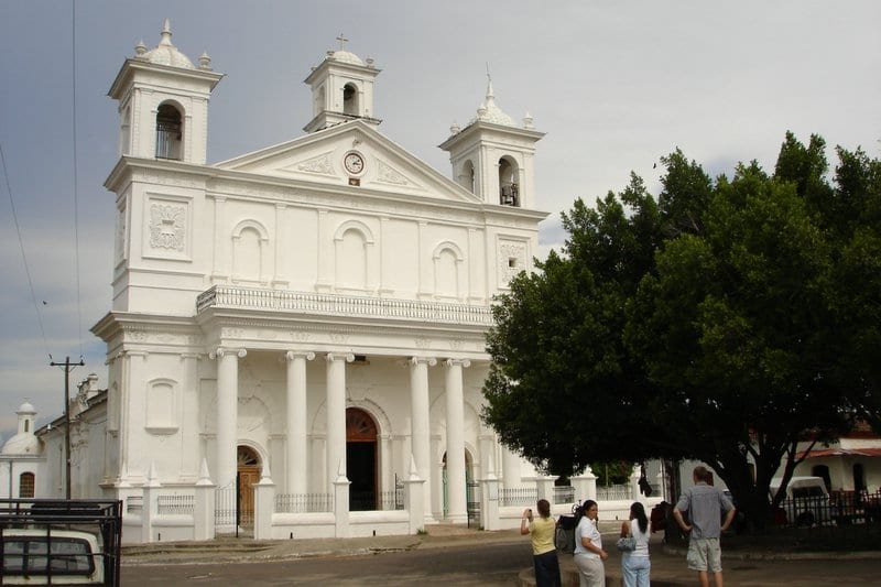 A whitewashed colonial church with twin bell towers on a cobbled plaza