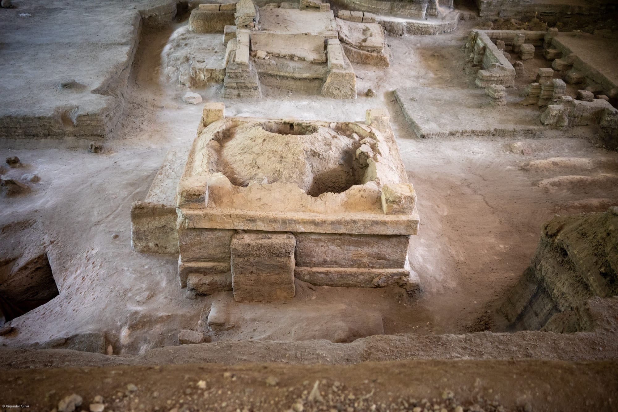 Excavated low adobe walls and a household shrine at an ancient buried village