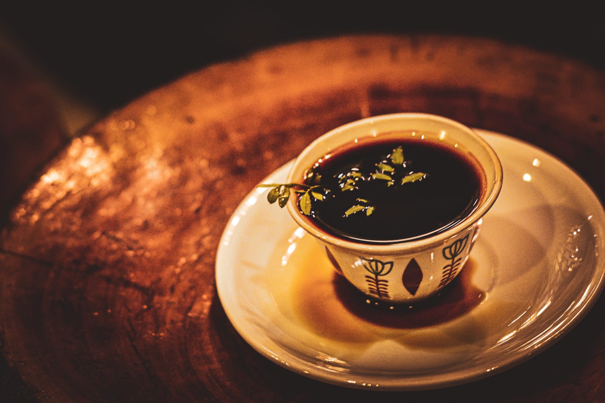 A small cup of coffee garnished with green herb leaves