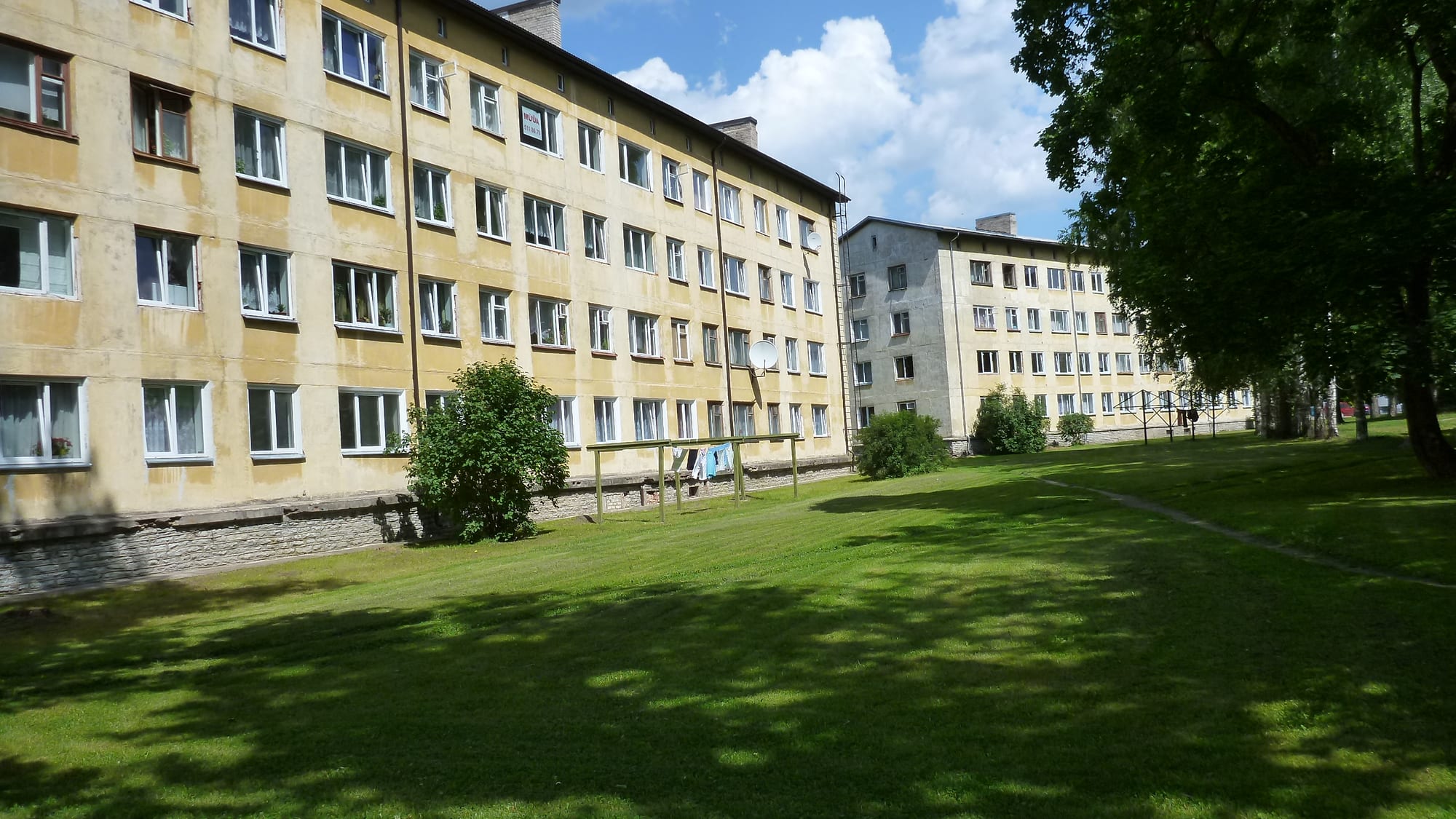 A row of Soviet-era concrete apartment blocks in Valga, Estonia, with washing lines and a grass courtyard