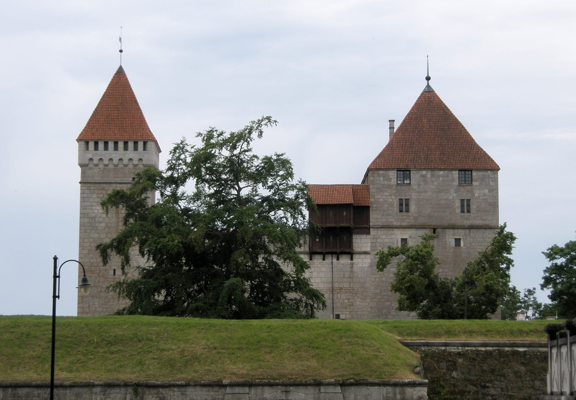 A compact grey stone castle with corner towers and a defensive moat