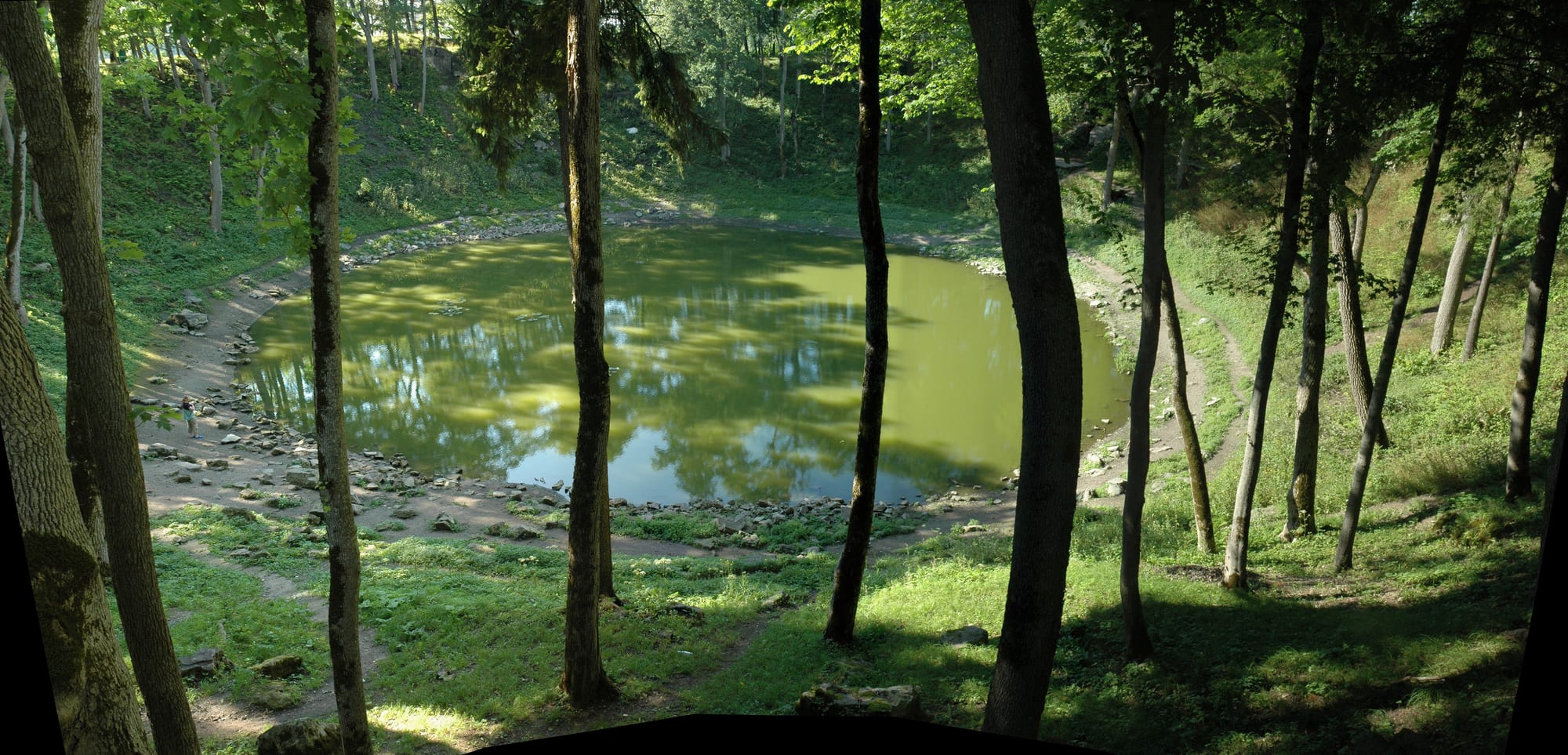 A near-circular pond in a ring-shaped depression surrounded by trees