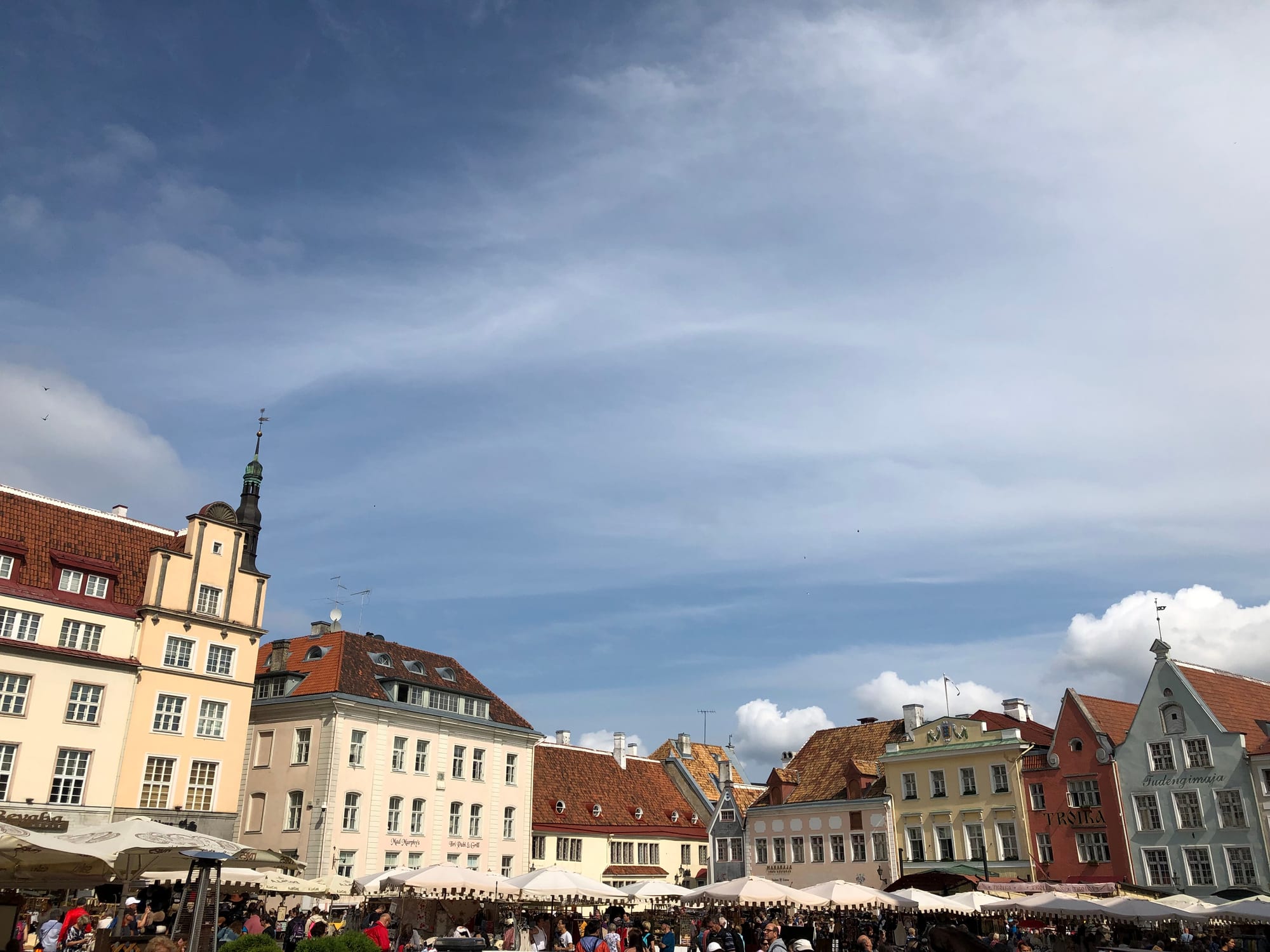 A cobbled square with a Gothic town hall tower and pastel merchant houses
