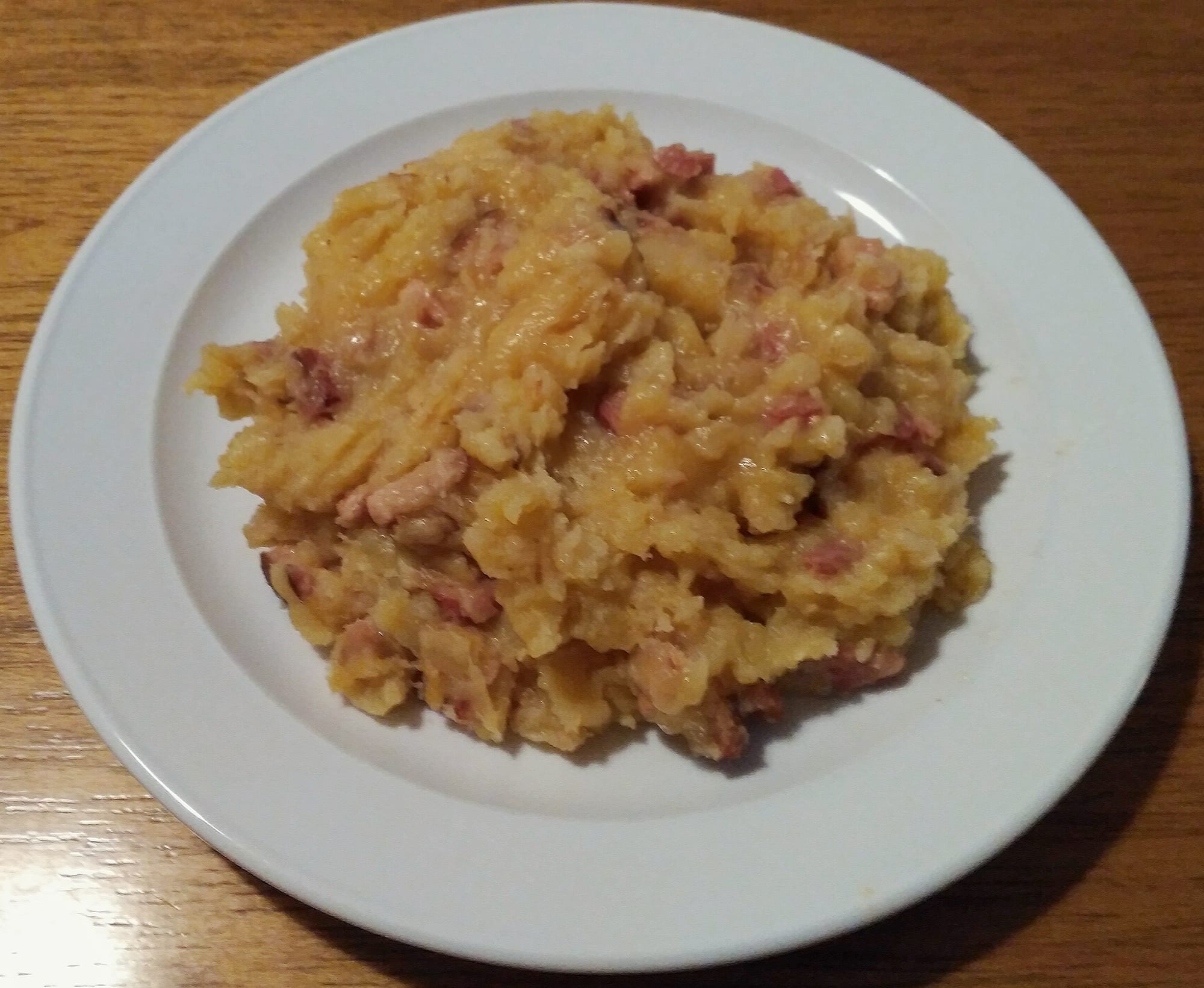 A bowl of pale porridge topped with crisp pork cracklings and chopped chives