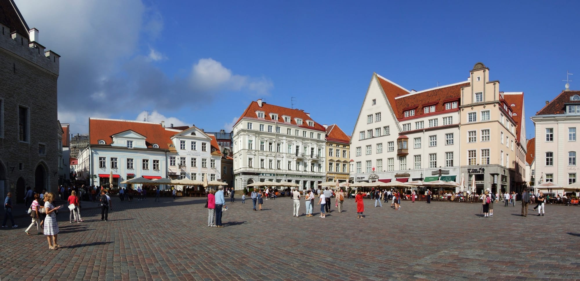 A cobbled square ringed by pastel merchant houses and the Gothic Tallinn Town Hall