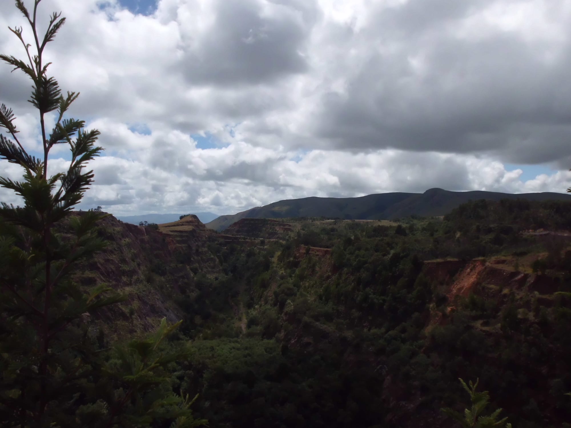 A red-earth open pit cut into a hillside, with the plains beyond
